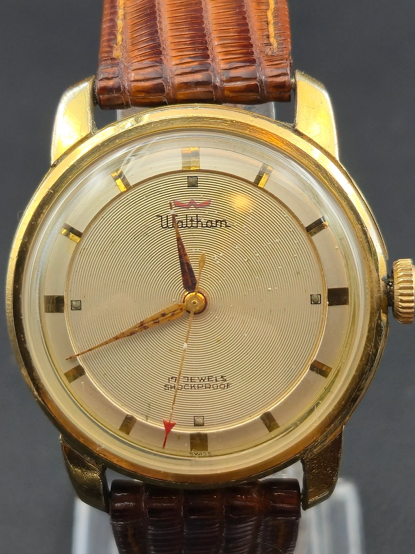Waltham Swiss 17J Manual Wind Gold Dress Watch 34 mm w/ Box (1950s–1960s): handsome vintage Waltham Swiss 17-jewel manual wind wristwatch featuring a 34 mm 10-karat gold-clad case with stainless-steel back. The champagne dial showcases a concentric guilloché pattern, applie