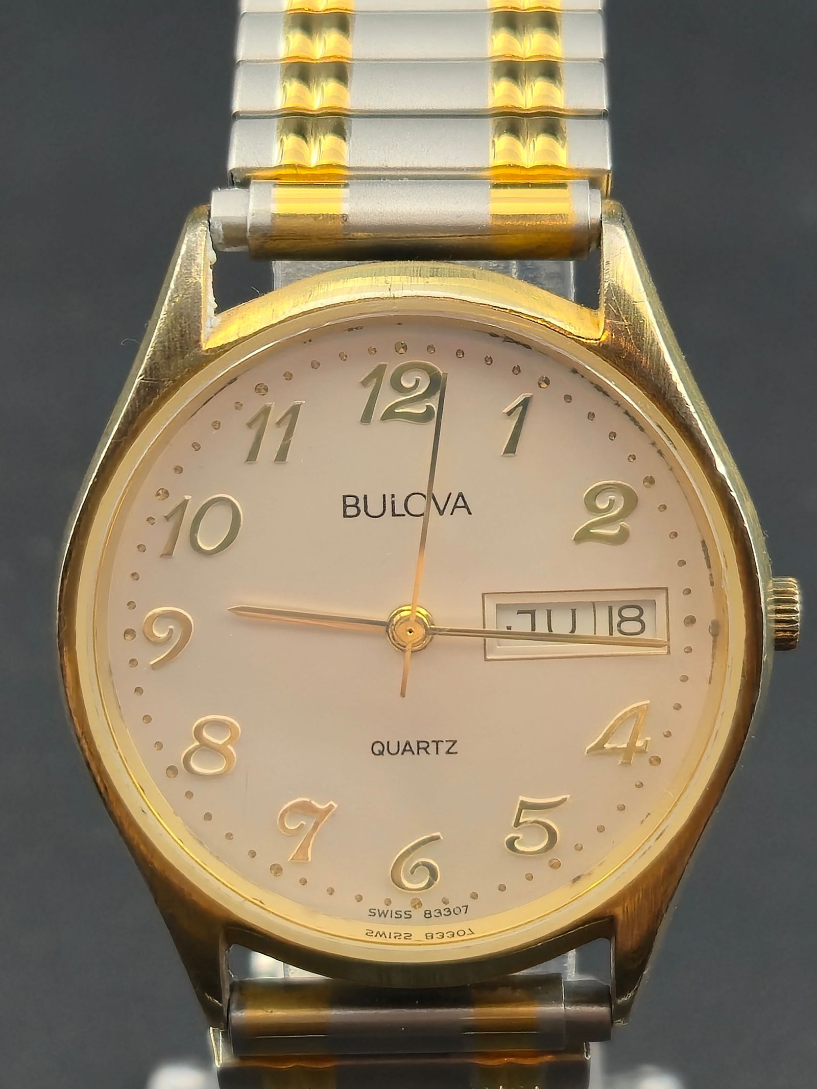 Bulova Quartz P3 Gold-Tone 36 mm Day-Date Watch with Two-Tone Expansion Band – New Battery: Classic Bulova Quartz men’s wristwatch featuring a clean gold-tone round case with a white dial and raised Arabic numerals. The simple design is complemented by a convenient day-date window at 3 o��