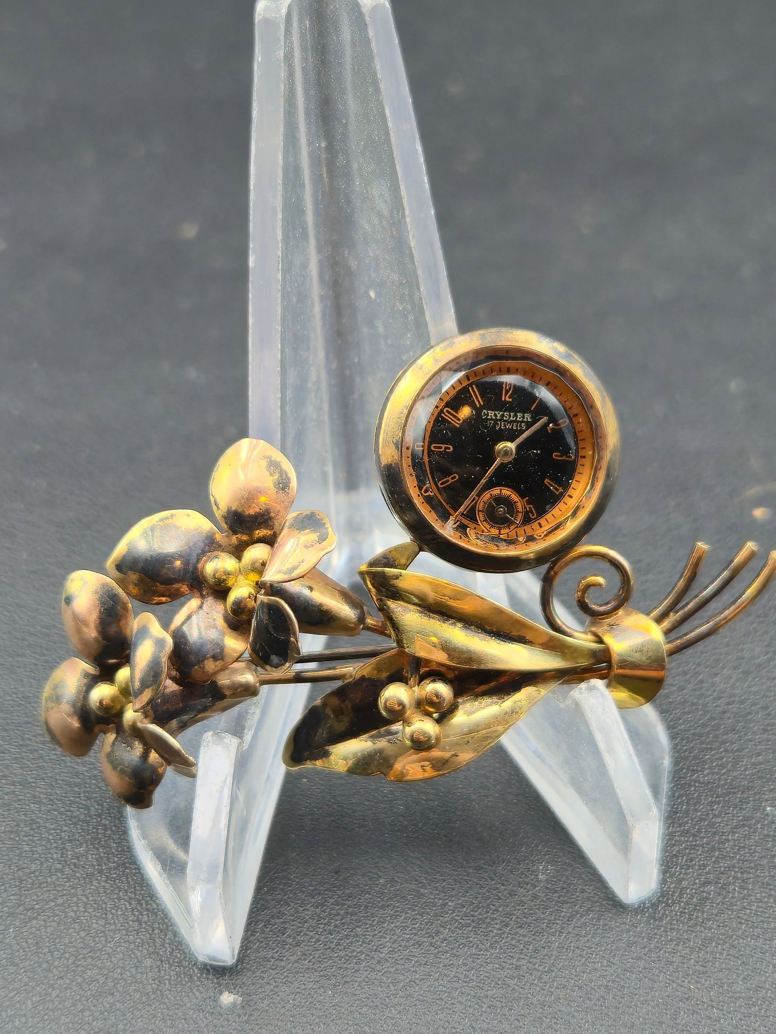1940s Crysler 17J Swiss Floral Brooch-Watch – 1/20 12K GF on Silver, PAT 130141 – Untested: Charming 1940s Crysler Watch Co. Swiss ladies’ brooch-watch, fashioned as a floral spray pin in sculpted yellow gold-filled over silver. The circular black dial is signed Crysler – 17 Jewels with 