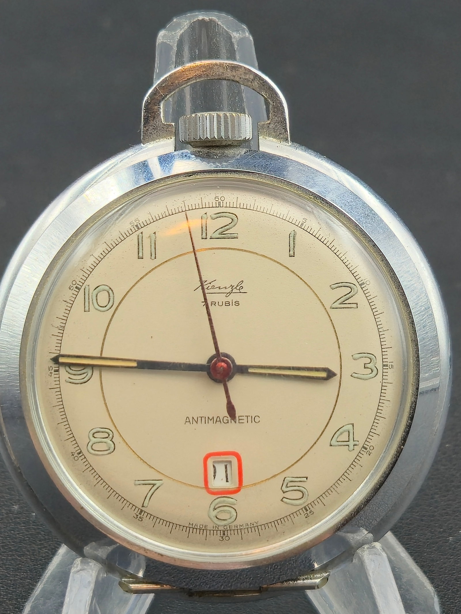 Kienzle 7J Antimagnetic 52.5mm Pocket Watch – Date Window – Chrome Case – Running: Offered is a vintage Kienzle pocket watch featuring a clean cream two-tone dial with Arabic numerals, center seconds, and a red-outlined date window at 6 o’clock. The dial is signed Kienzle – 7 Ru