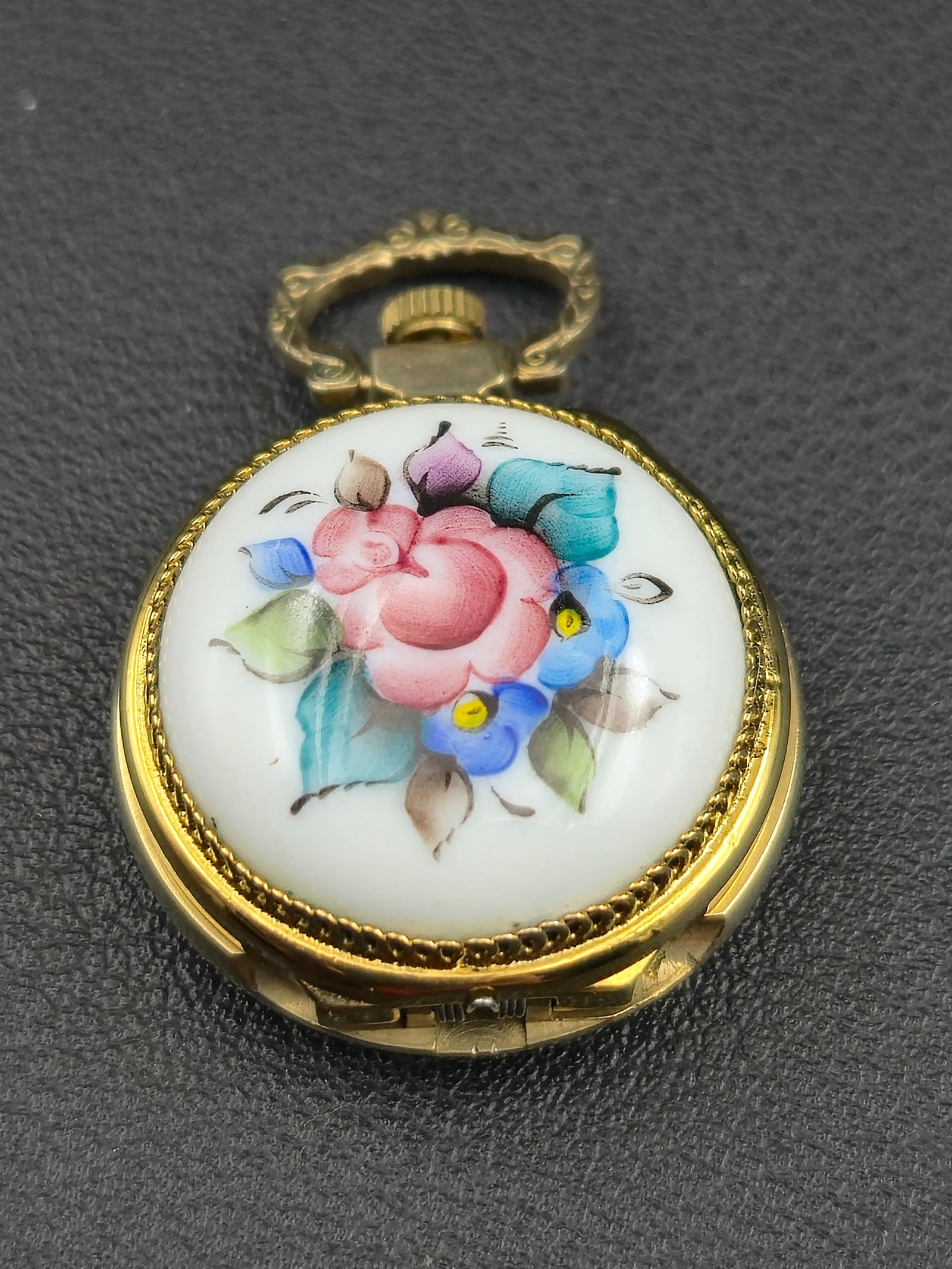 Chaika 17J 25mm Miniature Pendant Watch – Porcelain Enamel Floral Case – Running: Offered is a charming Chaika 17-jewel miniature pendant watch measuring 25 mm, featuring a beautifully hand-painted porcelain enamel floral lid and an ornate engraved rear cover. The inner dial displa