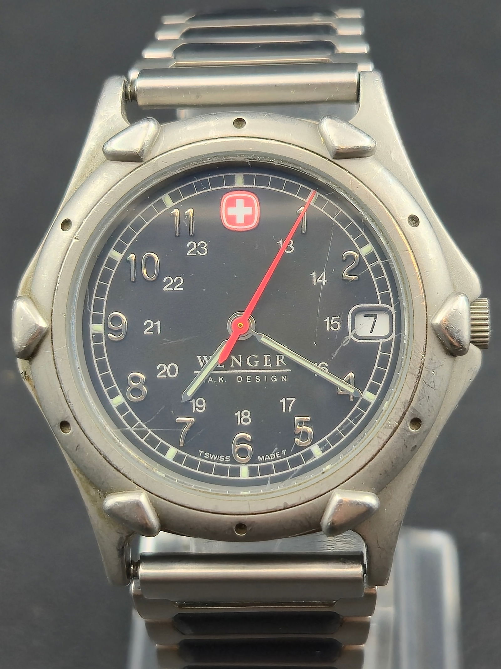 2000 Wenger A.K. Design Swiss Made 37mm Field Watch – Stainless – Black Dial – Runs: A classic early-2000s Wenger A.K. Design Swiss Made field watch featuring a rugged stainless-steel case, black military-style dial with 24-hour inner track, red seconds hand, and date display at 3 o��