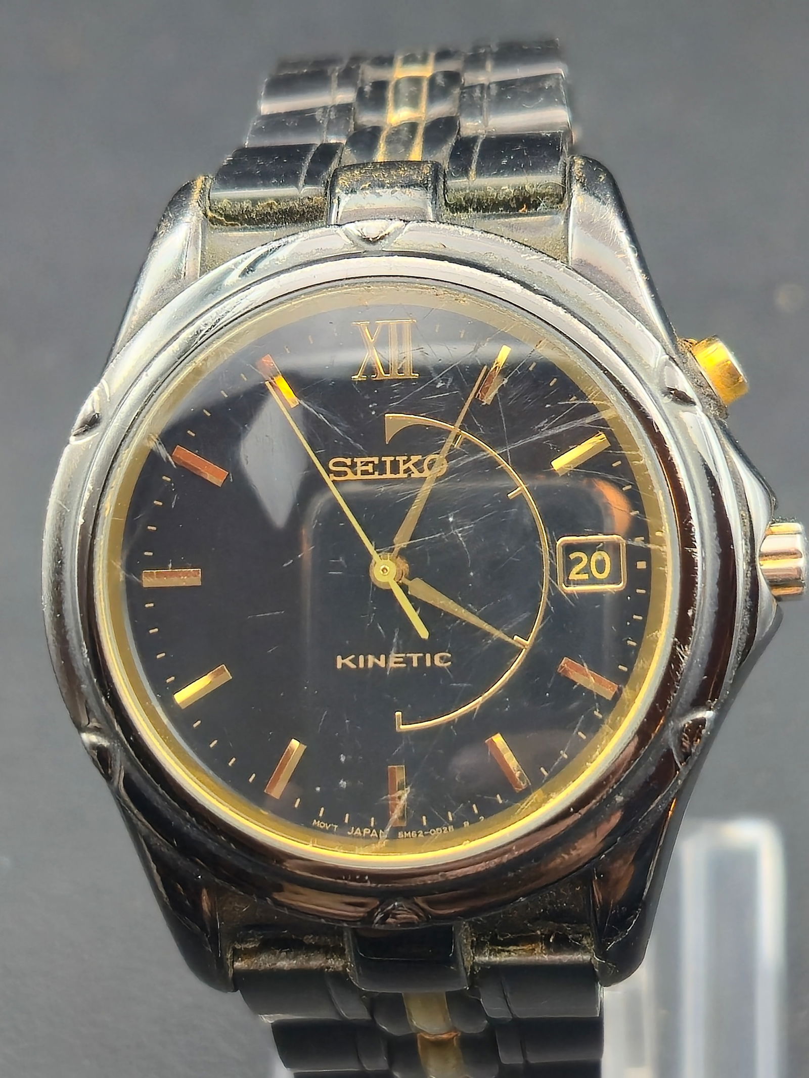 2000s Seiko Kinetic 5M62-0C80 “Black Gold Classic” 38mm Two-Tone Watch – Running: A vintage 2000s Seiko Kinetic reference 5M62-0C80 featuring a glossy black dial with gold-tone indices, Roman numeral XII, and date window at 3 o’clock. This model uses Seiko’s hybrid Kinetic tech
