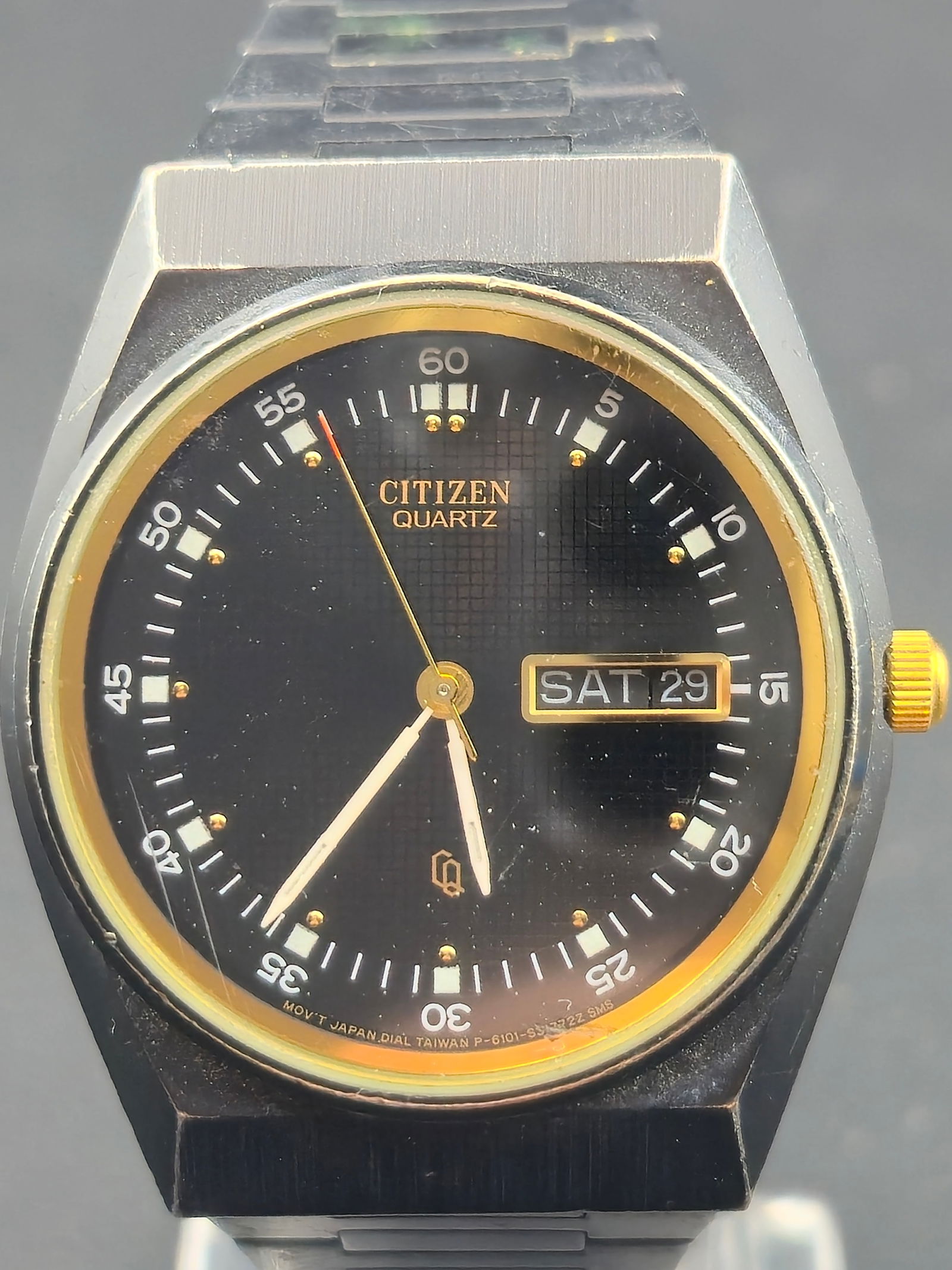 1989 Citizen Quartz 6101 Black Gold 35mm Vintage Day-Date Watch – Running and Keeping Time: Vintage 1989 Citizen Quartz day-date wristwatch featuring a black textured grid dial with gold accents and a matching gold day-date frame. Powered by the Japan-made Citizen 6101A quartz movement, this