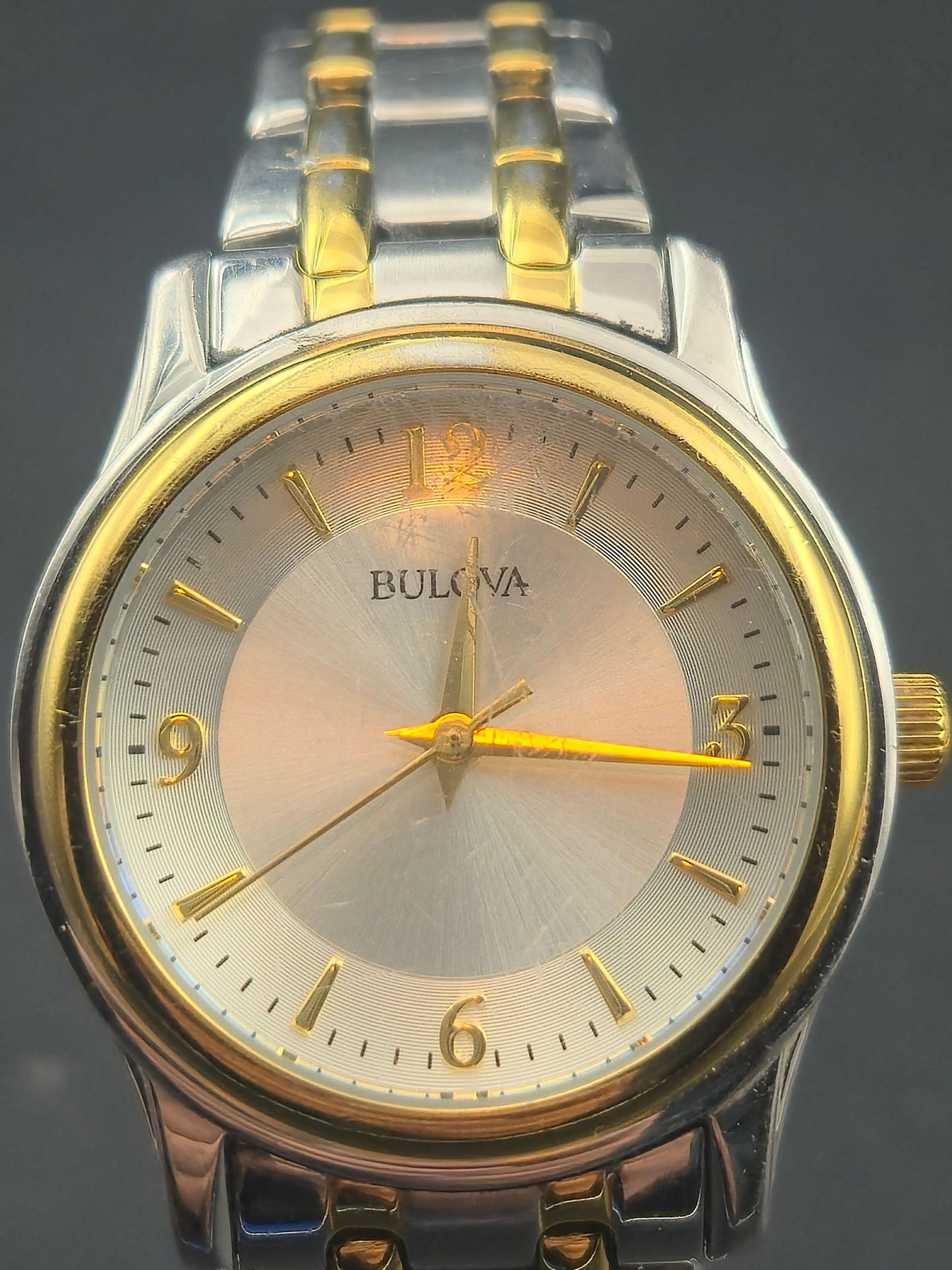 1998 Bulova Two Tone Quartz 30mm Classic Dress Watch – Running and Keeping Time – Stainless: Bulova two tone quartz dress watch from 1998 featuring a silver sunburst dial with gold hour markers and gold hands. The watch uses a stainless steel case with gold-tone bezel and matching two tone br