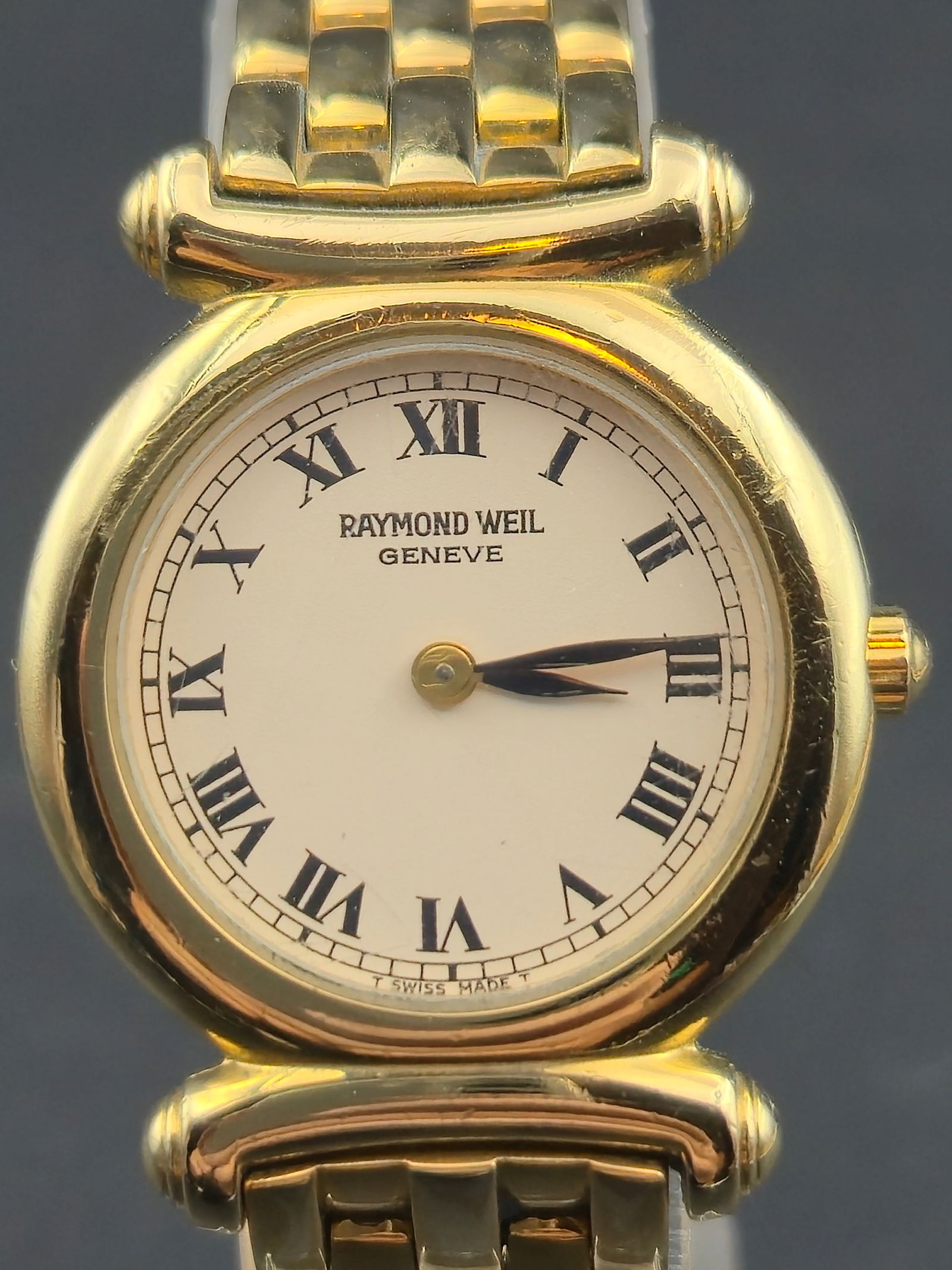1990s Raymond Weil 26mm Gold Electroplated Swiss Quartz Watch w/ Original Bracelet: Elegant 1990s Raymond Weil Genève ladies’ dress watch featuring a classic white Roman numeral dial and its original gold-electroplated bracelet. The watch is running and keeping time with a fresh b