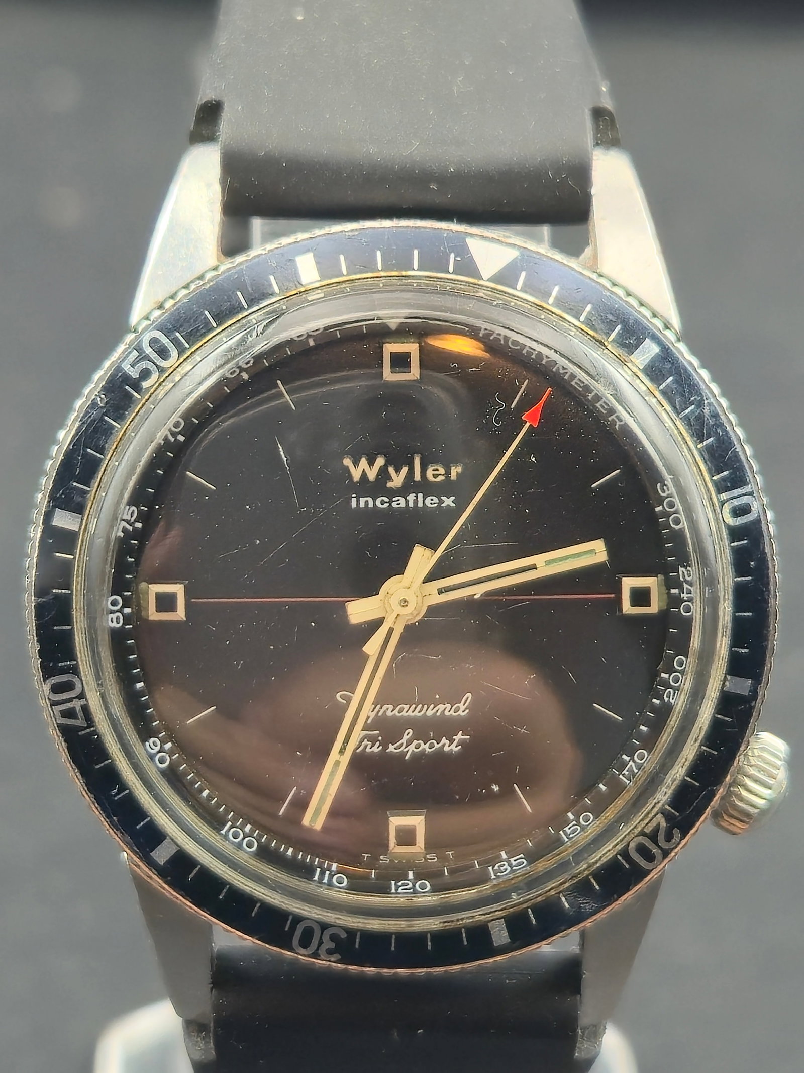 1960s Wyler Incaflex Dynawind Tri-Sport 35mm Black Dial Diver-Style Watch – Running: Vintage 1960s Wyler Incaflex Dynawind Tri-Sport wristwatch featuring a black dial, gold-tone hands and markers, and the classic Wyler Incaflex shock-absorbing balance system. The rotating black bezel 