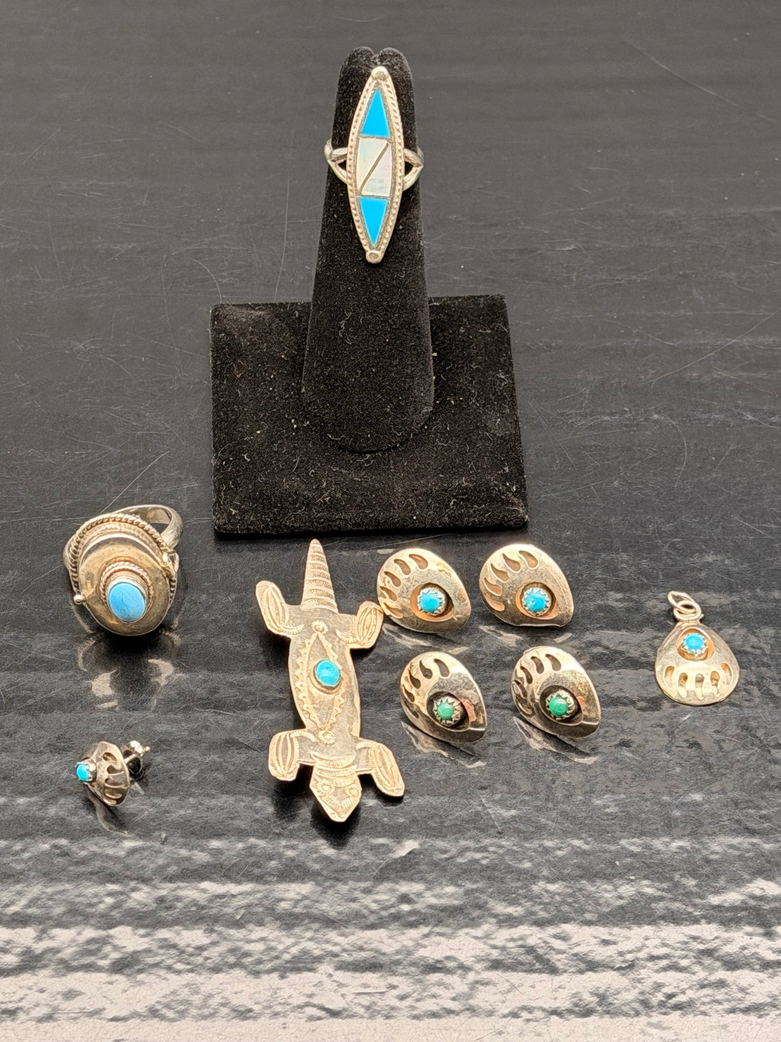 Vintage Sterling Silver Turquoise Jewelry Lot – Rings, Earrings, Brooch & Pendant – 23g: Beautiful mixed lot of vintage Navajo sterling silver jewelry, all featuring genuine turquoise stones.Includes:•2 sterling silver turquoise rings (one inlaid, one cabochon)•3 matching sterli