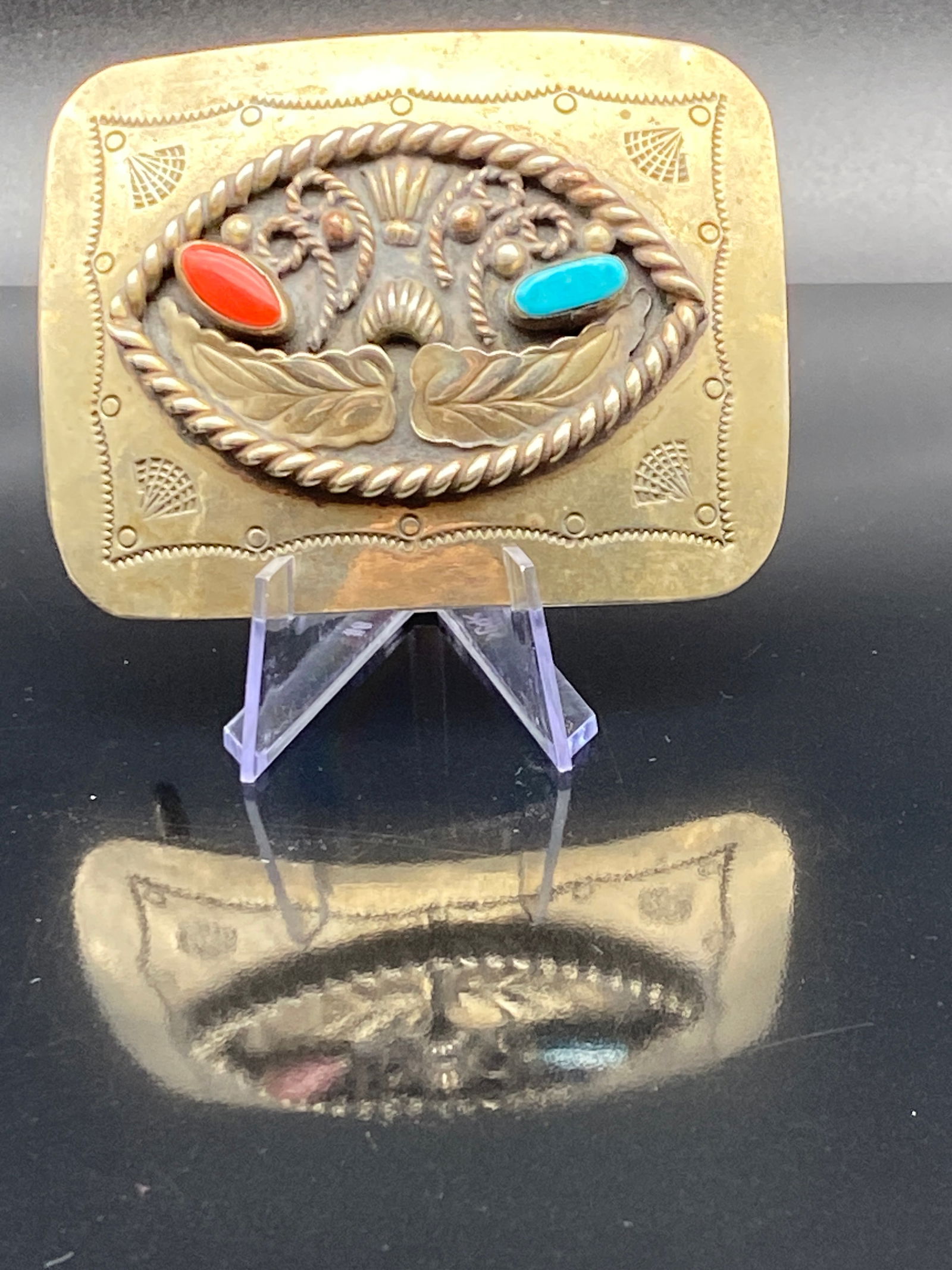 Brass Southwestern Belt Buckle w/ Coral & Turquoise: A vintage Southwestern-style brass belt buckle featuring detailed hand-tooled designs and two vibrant cabochons—one red (coral-colored) and one turquoise-colored. The central motif includes stylized