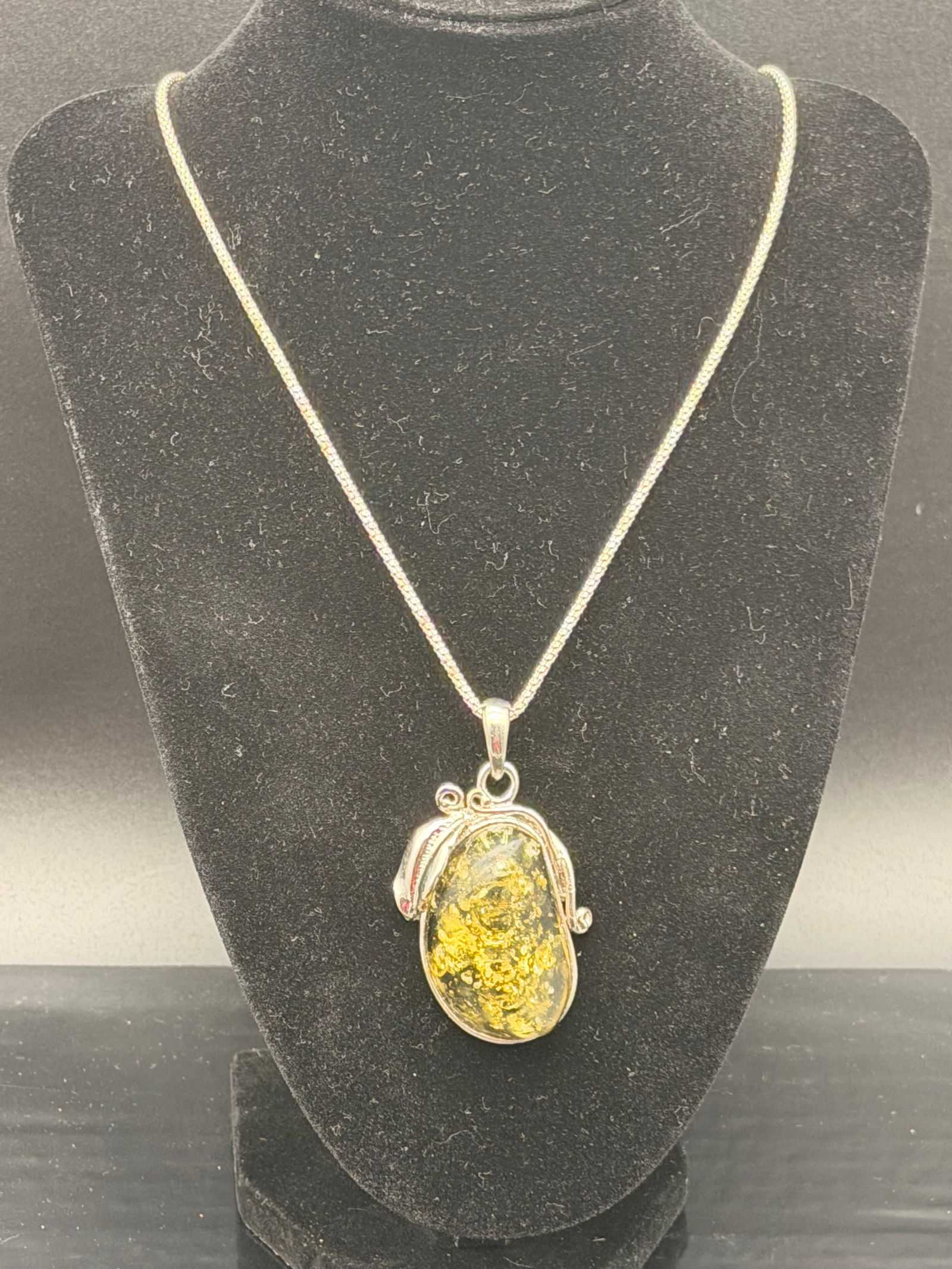 Green Baltic Amber Pendant Necklace in Sterling Silver – 29g: Elegant green Baltic amber pendant set in sterling silver with artistic vine/leaf detailing. Beautiful natural green amber with golden inclusions and excellent clarity.