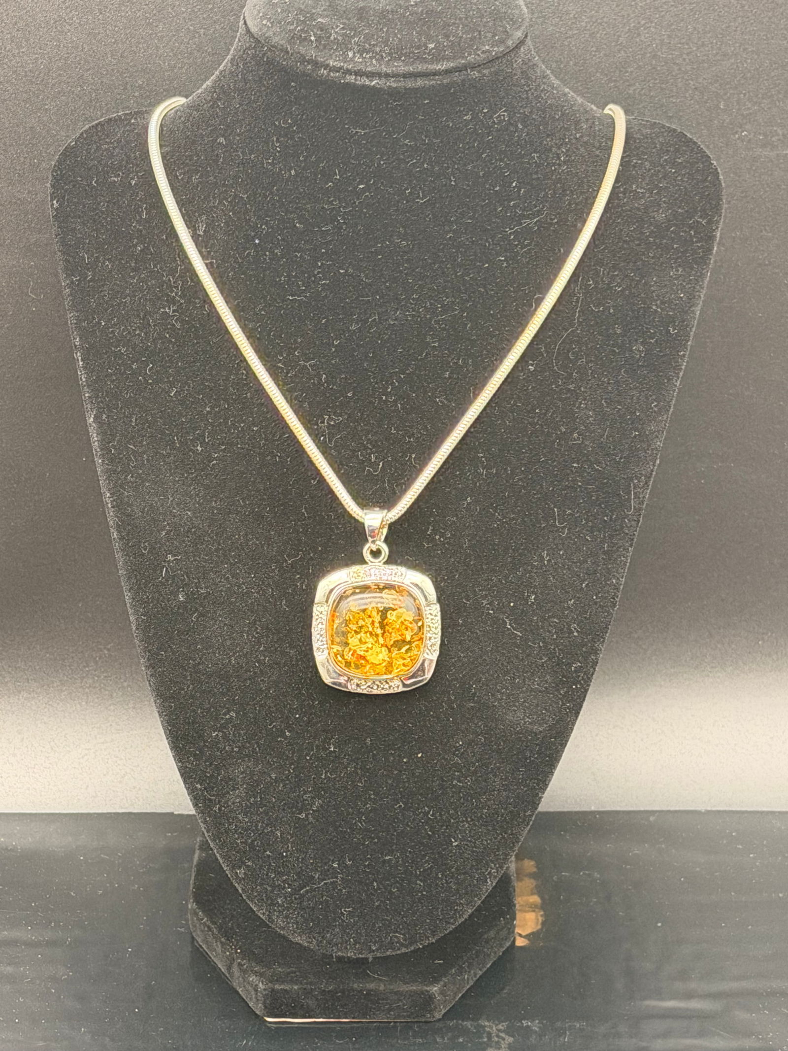 Modern Baltic Amber Pendant Necklace in Sterling Silver – 30g: Modern-style Baltic amber pendant set in sterling silver with decorative sparkling accents. Features warm golden amber with natural inclusions.