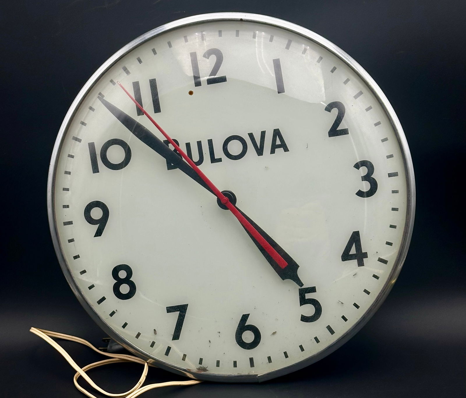 Vintage Bulova Electric Wall Clock – Working: Vintage Bulova electric wall clock with classic white dial, bold black numerals, and red second hand. Metal case with original glass front. Tested and working. Back shows original vents and bulb socke