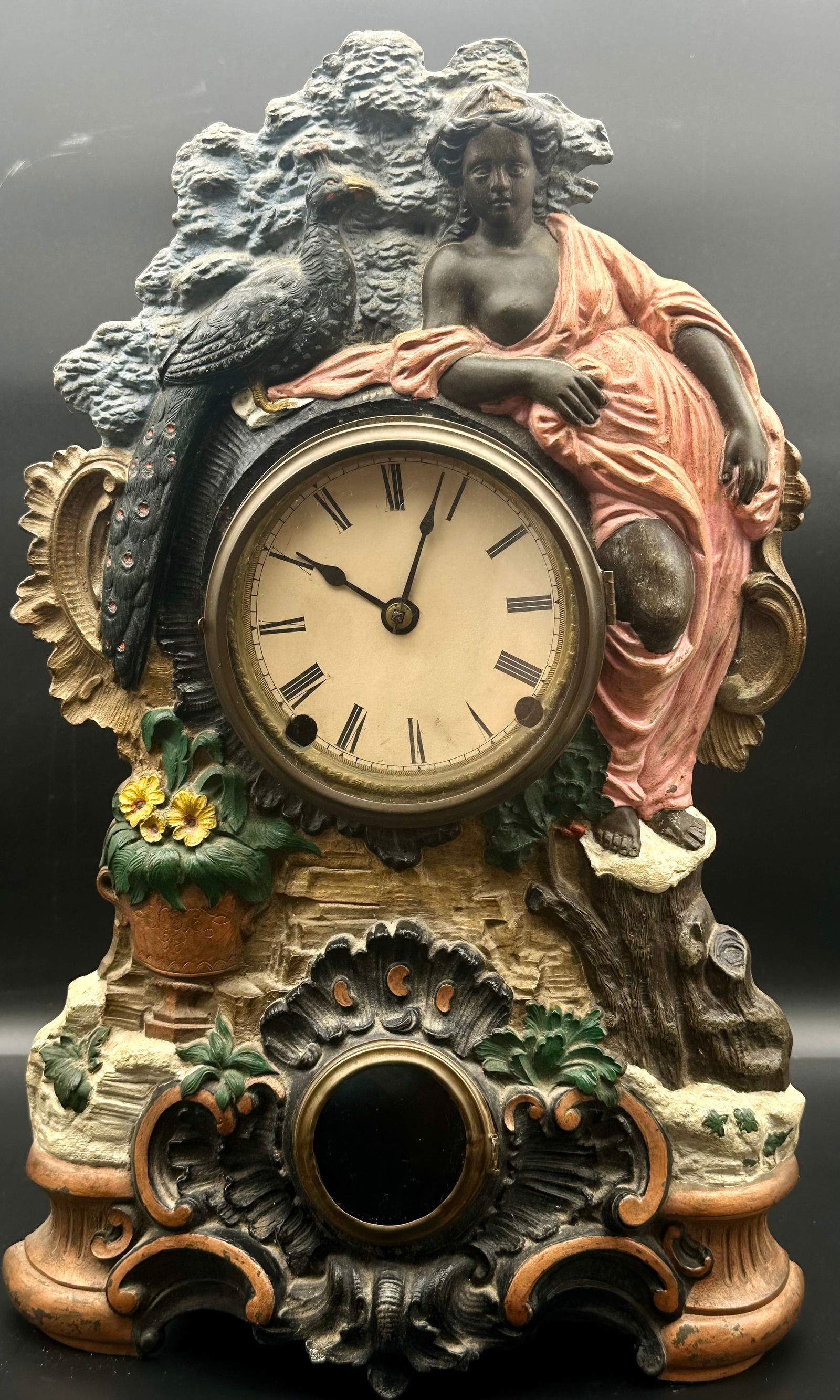 Antique European Figural Mantel Clock, Spelter, c. 1900: Late 19th–early 20th century European figural mantel clock featuring a classical female figure with bird, cast in painted spelter with architectural base. Enamel Roman numeral dial with hinged brass