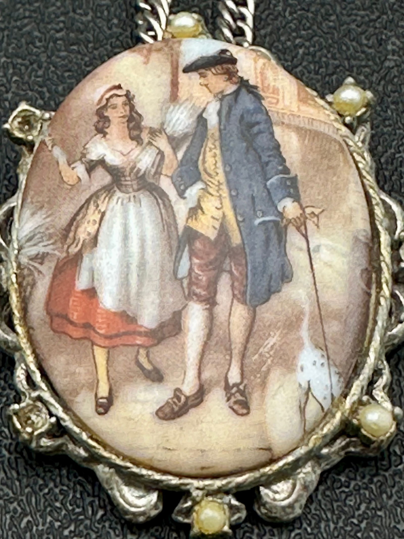 Vintage Silver Tone Necklace with Cameo-Style Romantic Scene Pendant: Vintage silver-tone necklace featuring an oval cameo-style pendant with a romantic pastoral scene beneath glass, framed by an ornate silver-tone mount. Several of the original faux pearl accents are m