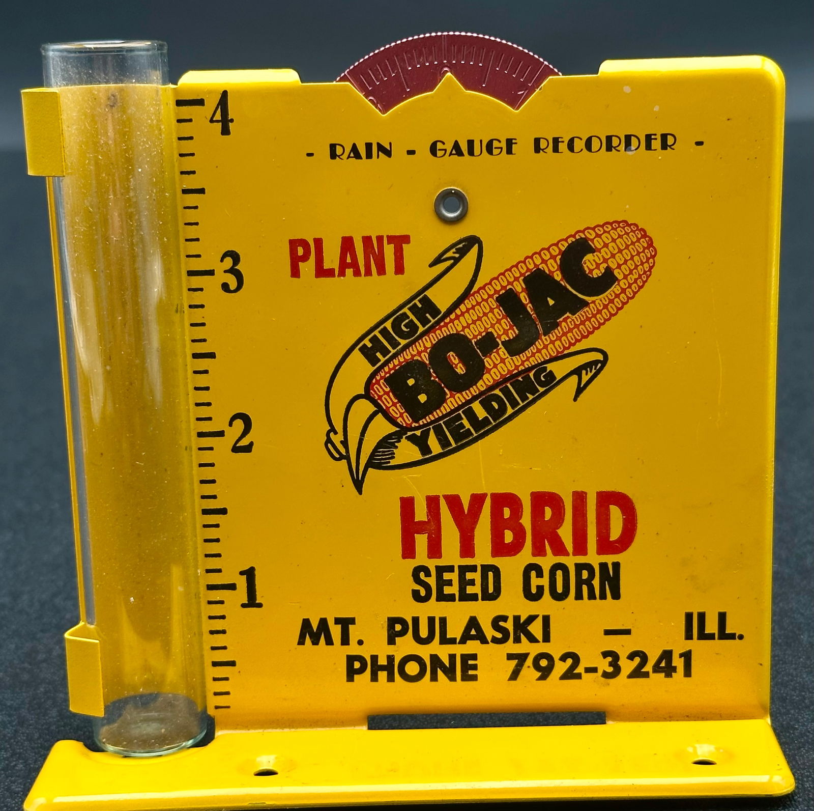 Vintage Bu-Lac Hybrid Seed Corn Advertising Rain Gauge Recorder – Mt. Pulaski IL: Vintage metal advertising rain gauge recorder for Bu-Lac Hybrid Seed Corn of Mt. Pulaski, Illinois. Features original glass measuring tube and bright yellow painted graphics with “Plant High Yieldin