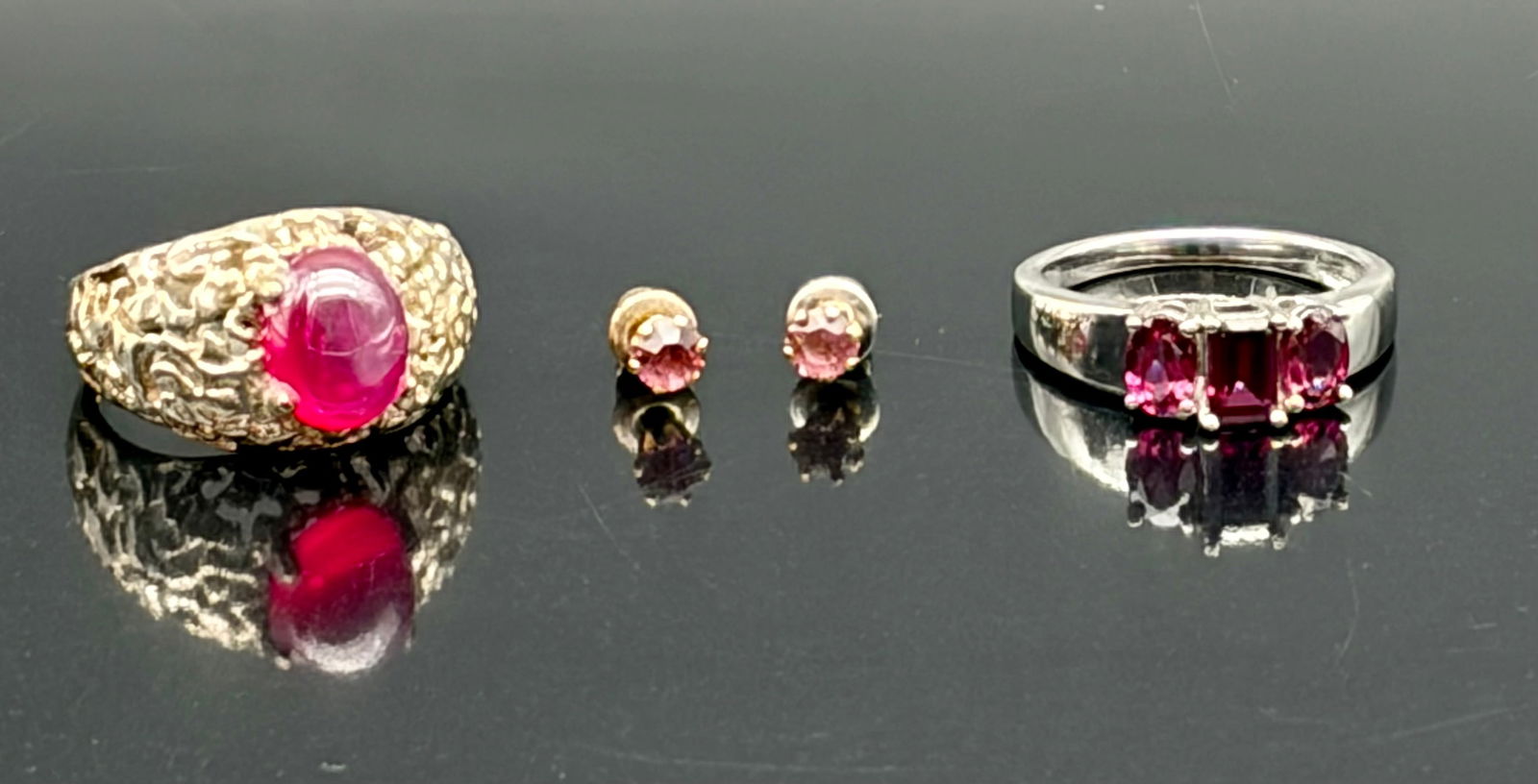 Two Rings & Earrings Pink Stone Jewelry Lot: Attractive three-piece jewelry lot featuring vivid pink stones. Includes a bold gold-tone ring set with a cabochon-style pink center stone in a textured sculptural setting, a pair of gold-tone stud ea