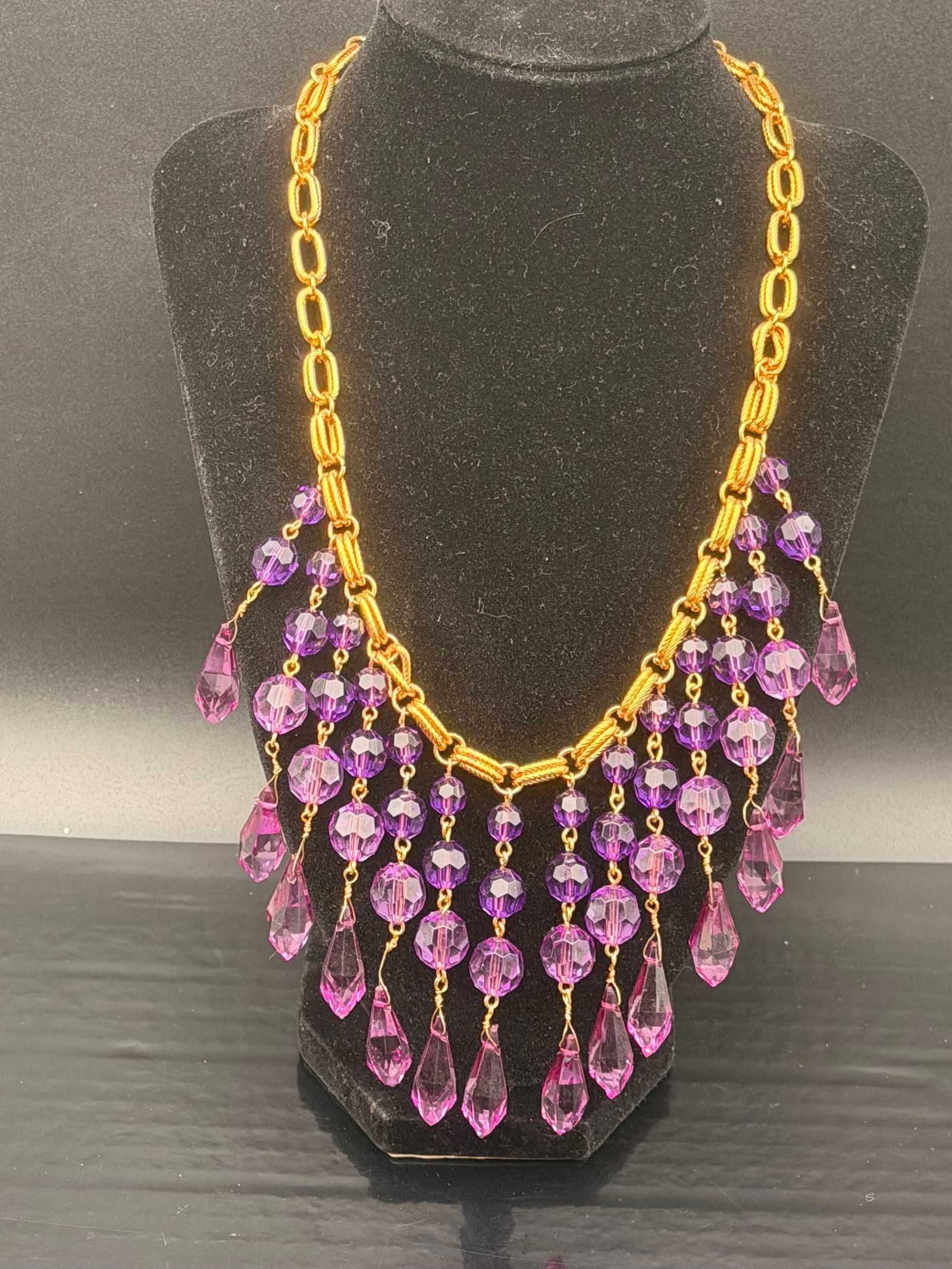 Vintage Gold-Tone Purple Crystal Waterfall Statement Necklace – 72g: Bold and eye-catching vintage statement necklace featuring vibrant purple faceted crystals in teardrop and round shapes, suspended from a rich gold-tone chain.