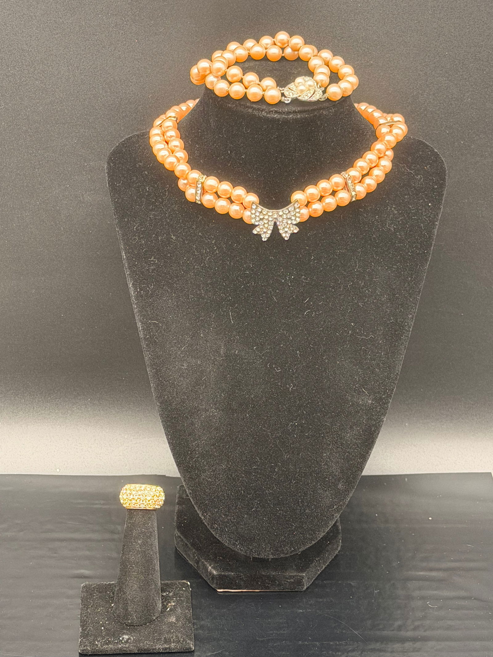 Vintage Peach Faux-Pearl Jewelry Lot – Multi-Strand Necklace, Bracelets & Cocktail Ring – 71g: Beautiful vintage peach faux-pearl jewelry assortment weighing a combined 71 grams. This lot includes a lovely double-strand necklace with a rhinestone bow centerpiece, matching bracelets, several add