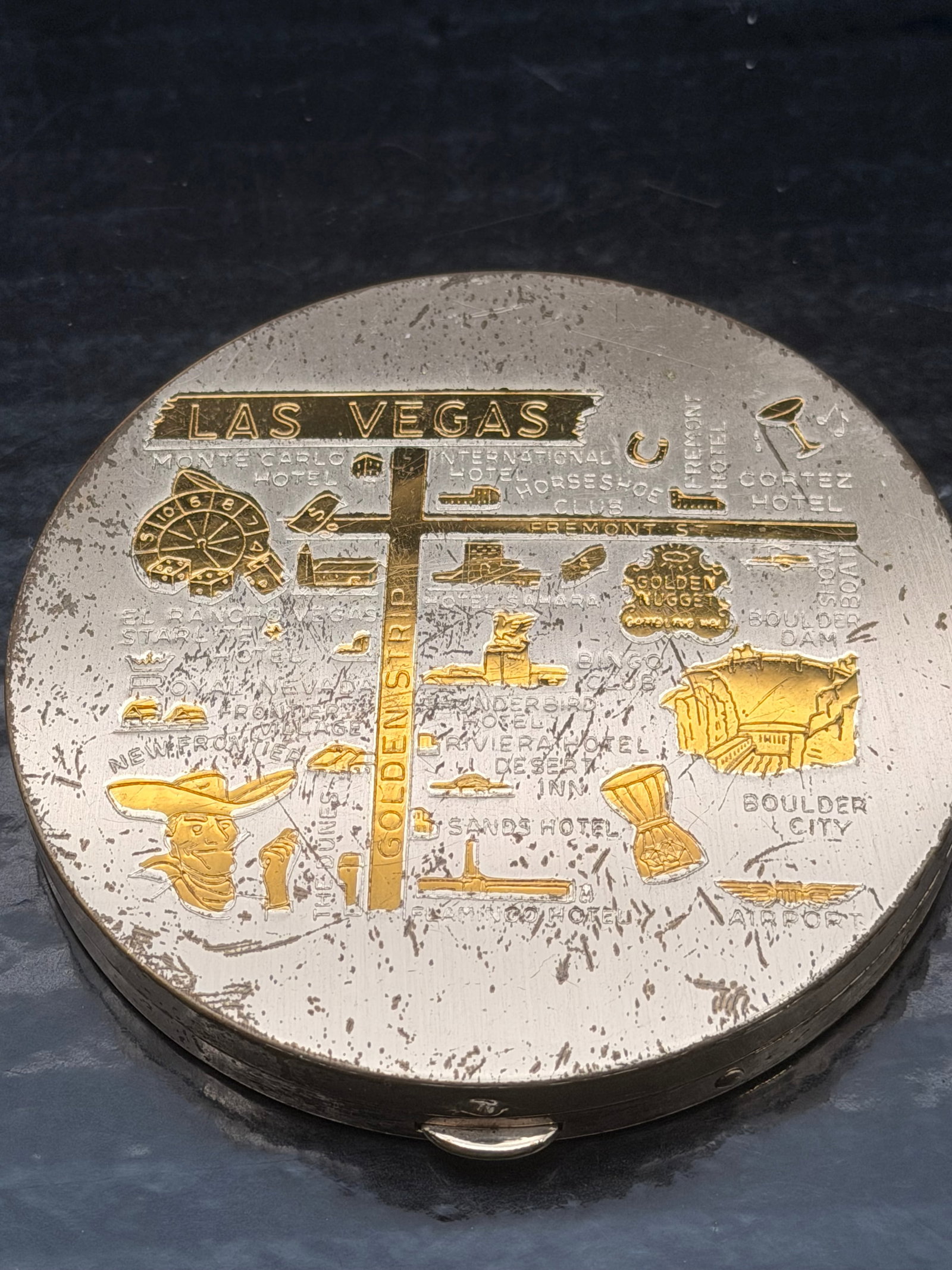 Vintage Las Vegas Souvenir Compact – 106g: Beautiful vintage metal makeup compact featuring a raised Las Vegas map design with classic landmarks highlighted in gold-tone accents (Golden Nugget, Boulder City, Fremont St., Horseshoe, El Cortez, 