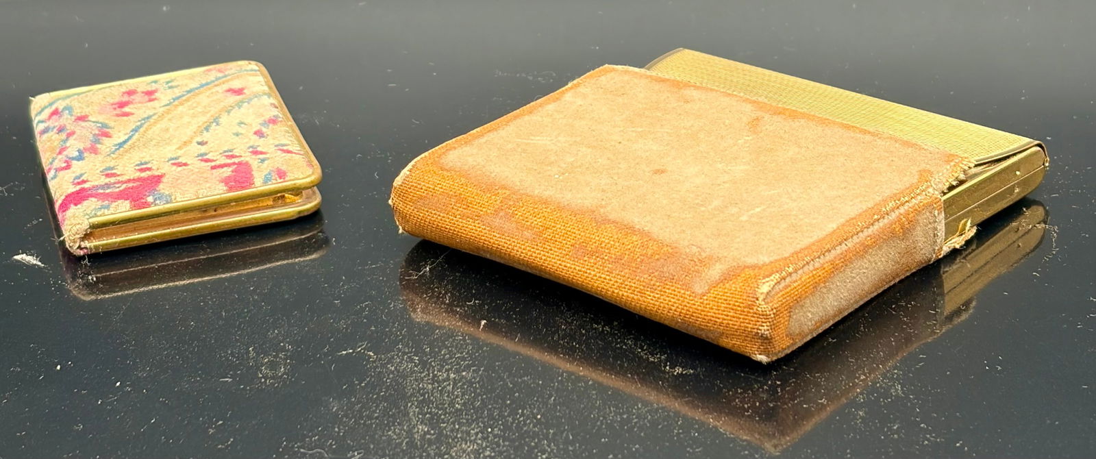 Vintage Gold-Tone Powder Compacts, Fabric Covers: A pair of early to mid-20th century ladies’ powder compacts presented in gold-tone metal casings, each retaining original interior components. One example features a floral tapestry-style fabric cov