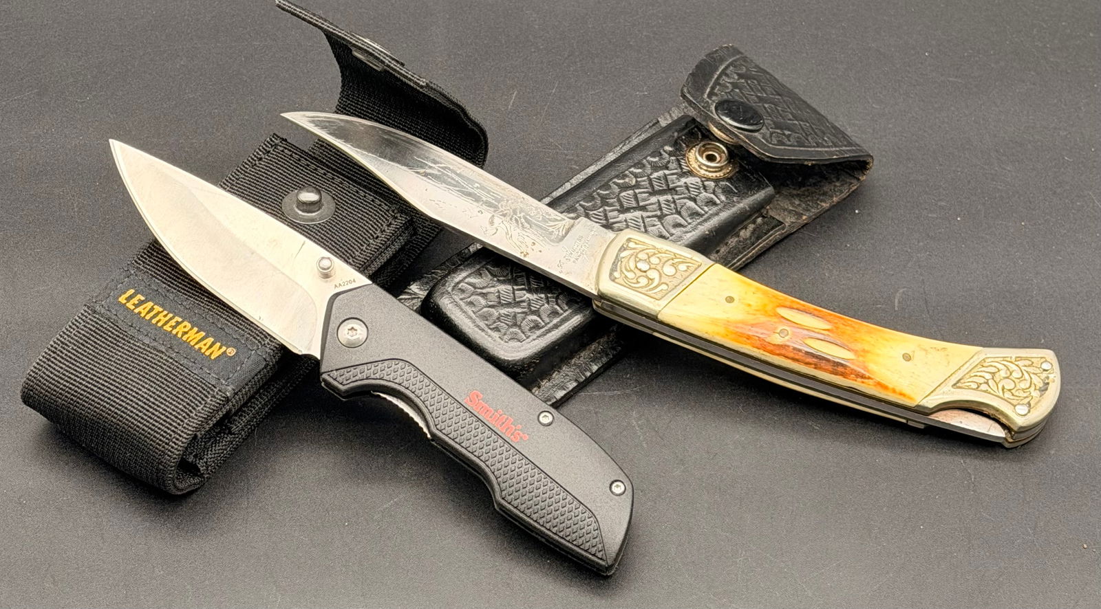 2-Knife Lot – Old Smoky Fixed Blade + AA2204 Folding Pocket Knife – Vintage & Modern Knife Set: Lot of two knives sold together:1. Old Smoky Fixed Blade Knife•Vintage hunting-style fixed blade•Engraved deer/wildlife scene on the blade•Faux bone handle with ornate metal bolsters&bu