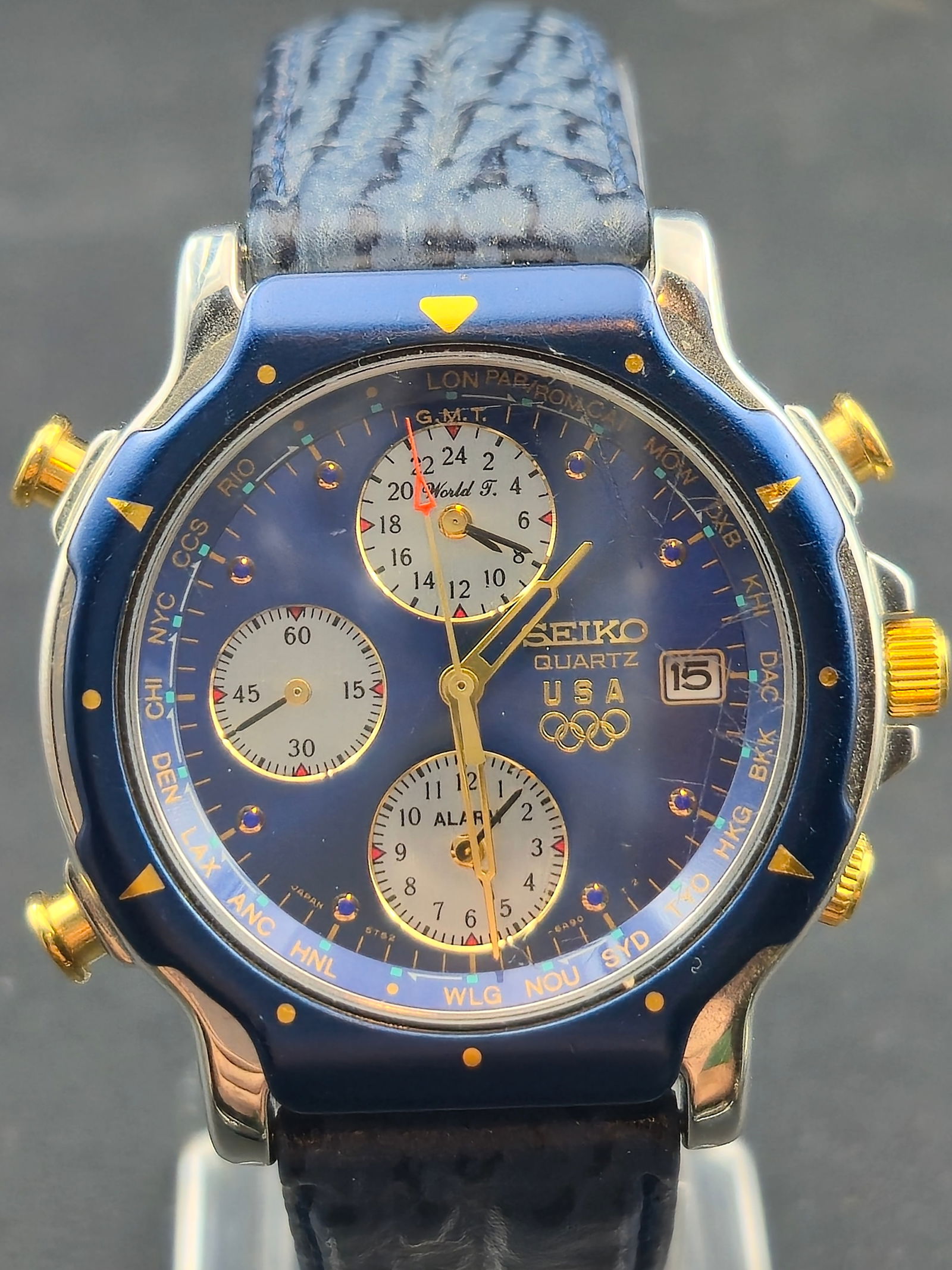 1991 Seiko 5T52 USA Olympic Edition World Time Alarm Chronograph 37mm Blue Dial New Battery Running: Rare 1991 Seiko USA Olympic Edition world time alarm chronograph, reference 5T52-6B09, featuring a glossy blue dial with gold-tone hands, Olympic rings logo, multiple subdials, and world-city ring. Fu