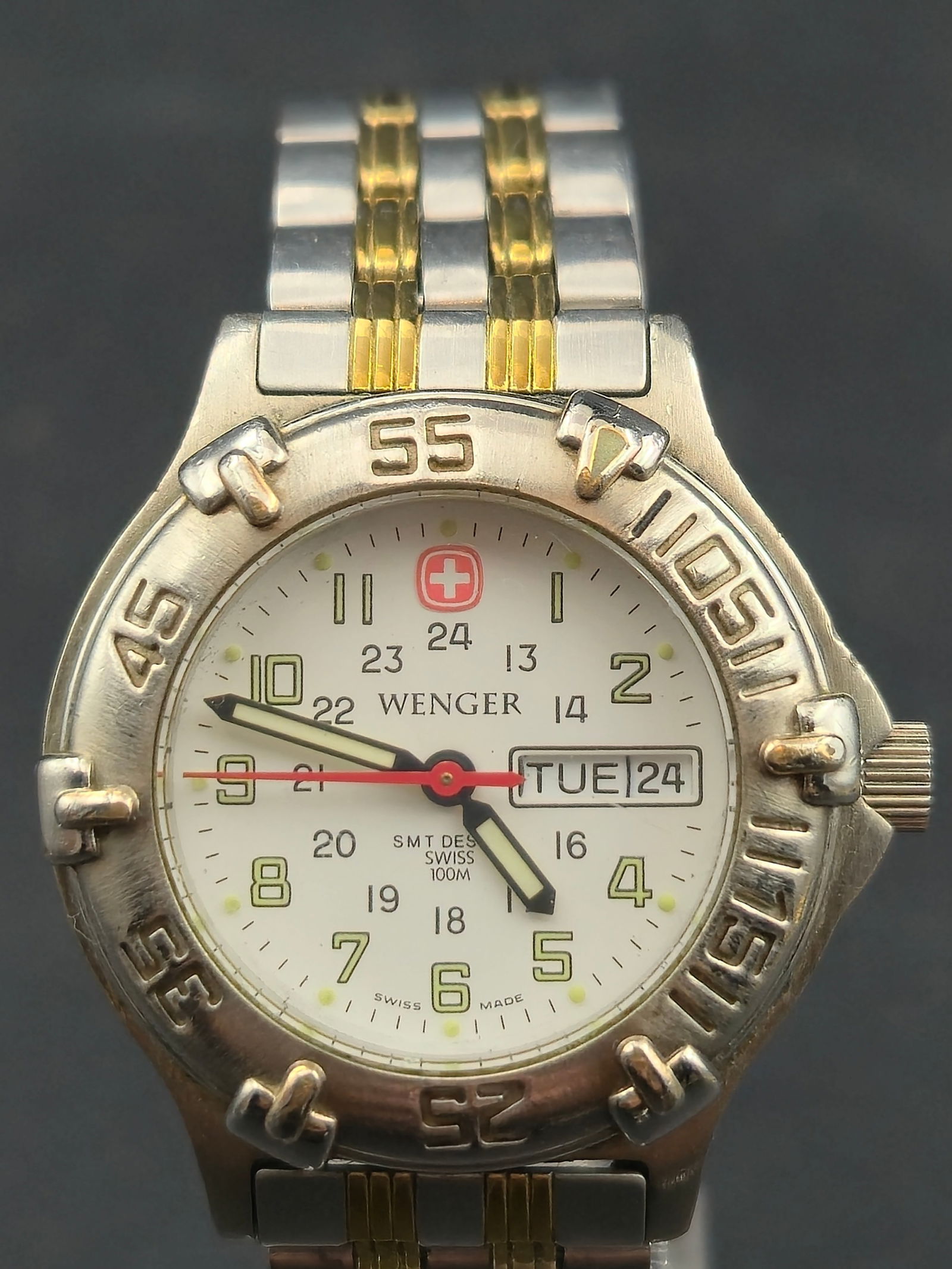 Wenger SMT Design 29mm Swiss Quartz 100M Two-Tone Field Watch Day-Date New Battery Running & Keeping: Wenger SMT Design Swiss-made field watch featuring a 29mm stainless steel and gold-tone case with a unidirectional style sport bezel and a crisp white dial with 12- and 24-hour markers. Powered by a r