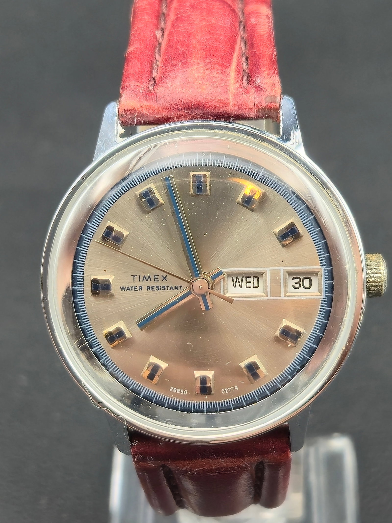 Vintage Timex Day-Date 35mm Silver Sunburst Dial Mechanical Watch – Runs: This vintage Timex Day-Date features a classic silver sunburst dial with blue-accent markers, framed by a clean polished bezel. The watch is running and displays both day and date. A great example of