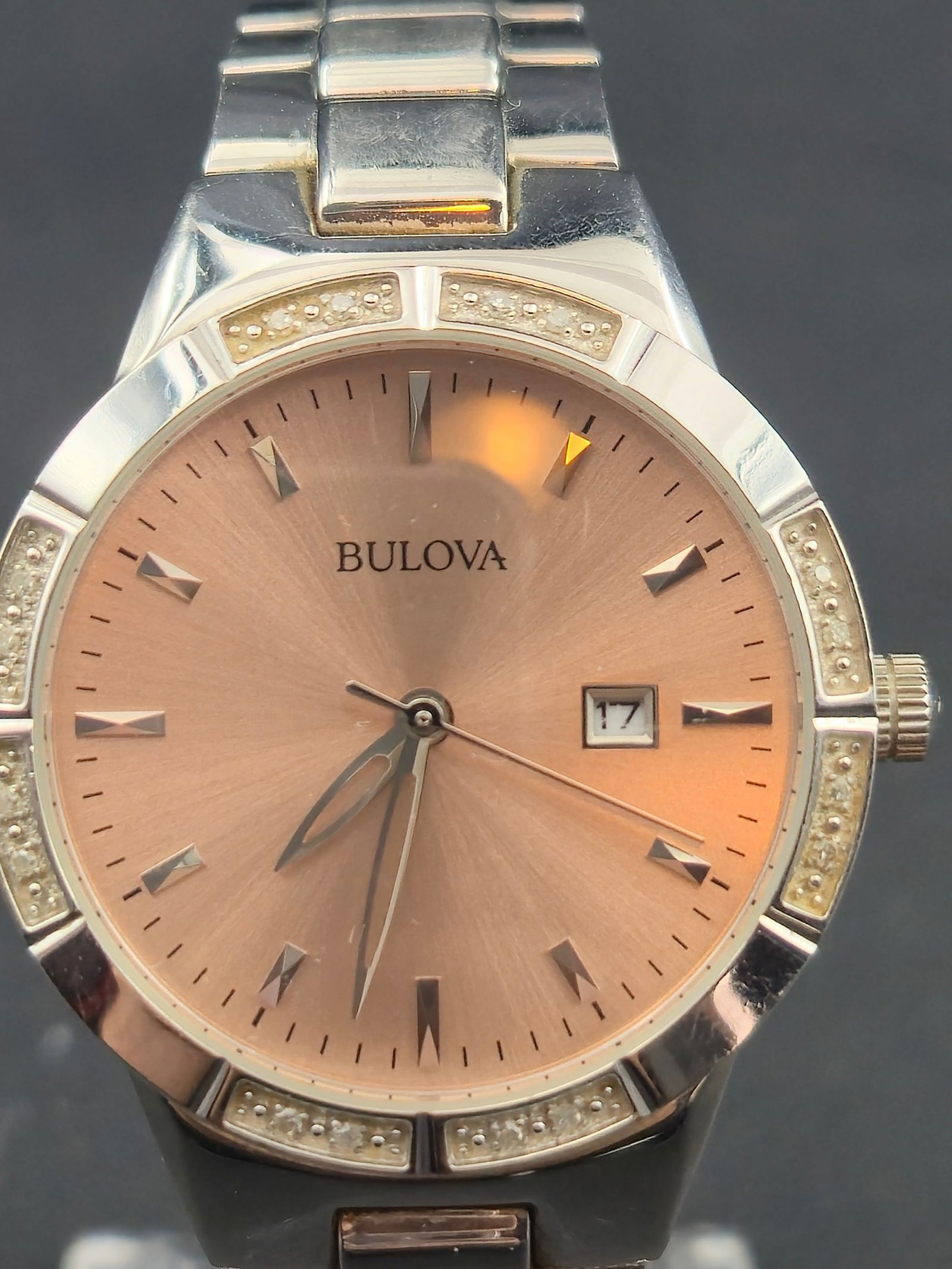 Bulova 32mm Pink Sunburst Dial Stainless Steel Quartz Dress Watch – New Battery: This elegant Bulova women’s dress watch features a refined pink sunburst dial, faceted hour markers, and a polished stainless-steel bracelet. The bezel is accented with raised decorative beadwork, g