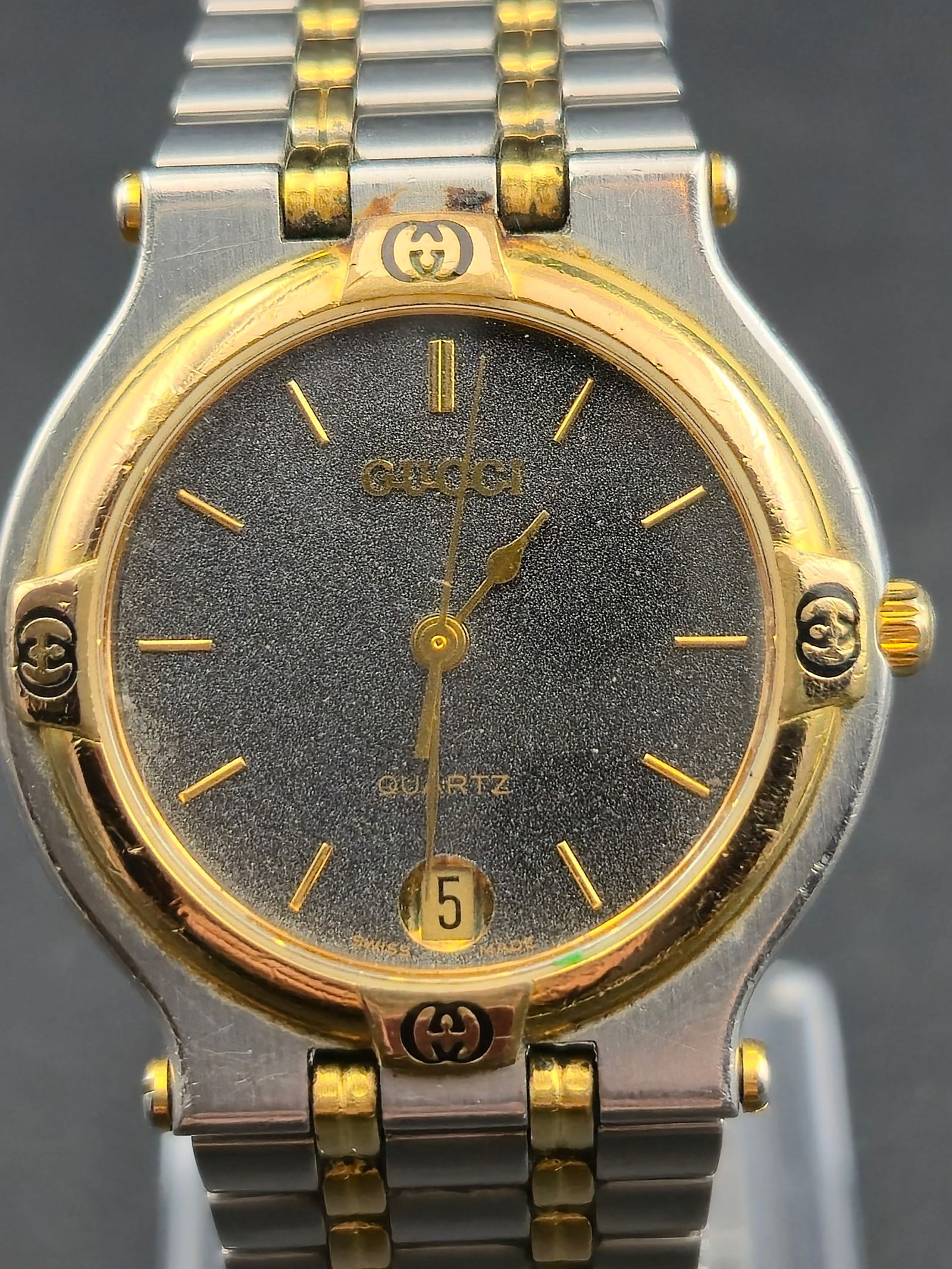 Gucci 9000M Two-Tone 32mm Quartz Watch – Swiss Made – New Battery: This authentic Gucci 9000M two-tone wristwatch features the iconic 1990s Gucci design with gold-tone G-logos on the bezel, original two-tone bracelet, and a clean Swiss quartz movement marked GUCCI in