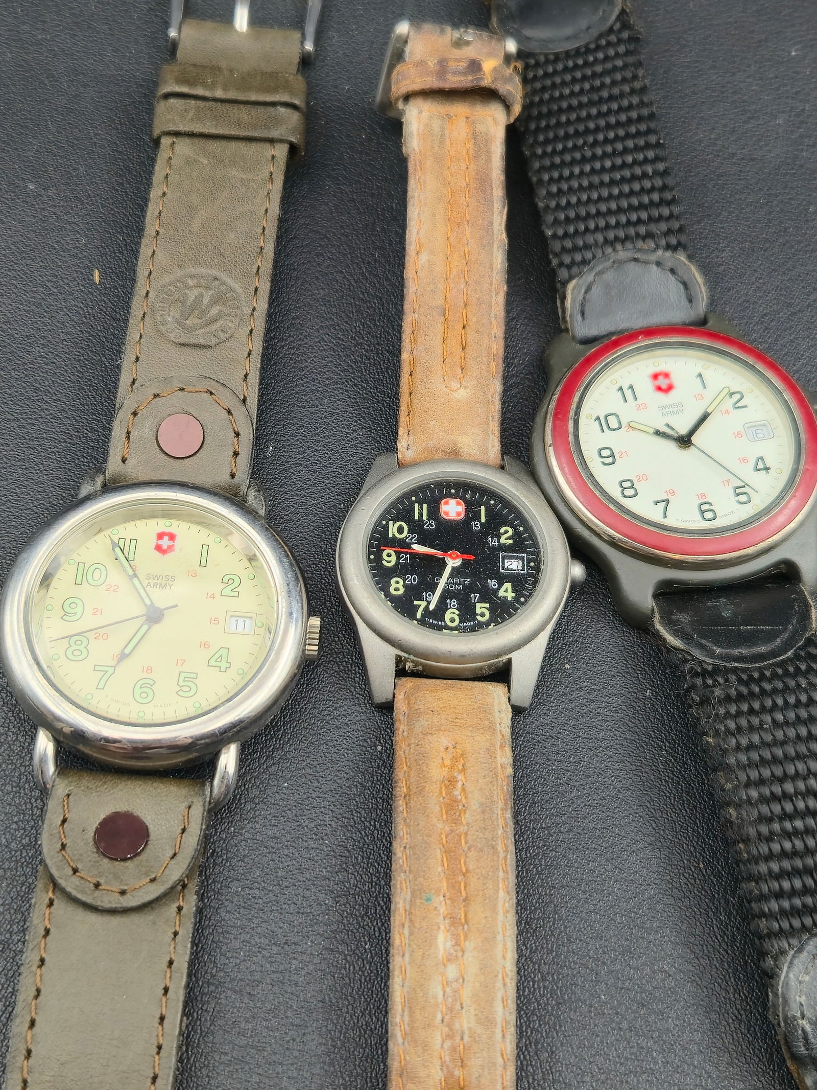 1990s Lot of 3 Swiss Army Marlboro Watches Quartz 36–38mm: A mixed lot of three 1990s Swiss Army–branded “Marlboro Adventure Team” quartz field watches, including two date models and one 50m diver-style variant. All are being sold untested. Cosmetic