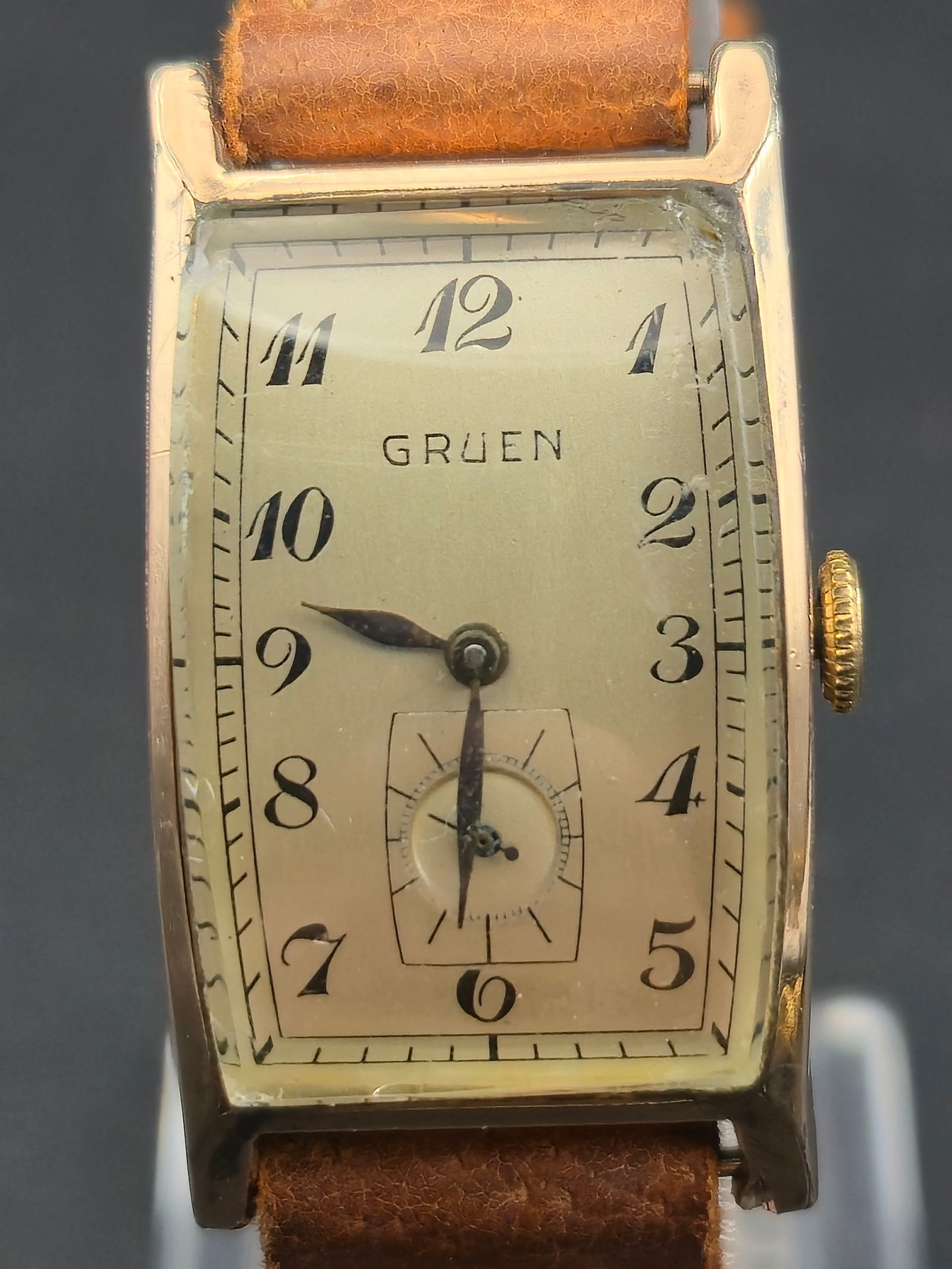 1940s Gruen Tank 20mm 10K GF Bezel 17J Swiss Manual-Wind Rectangular Dress Watch Running: Presented is a 1940s Gruen rectangular dress watch featuring a curved 10K gold-filled tank-style bezel and a classic cream dial with bold Arabic numerals and a sub-seconds register at 6 o’clock. Pow
