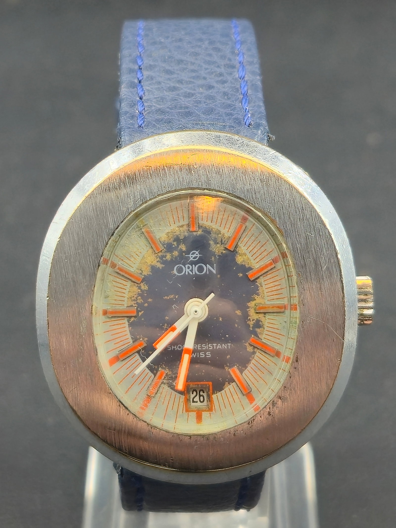 1970s Orion Swiss 1J Mechanical 37.6mm Date Wristwatch Base Metal SS Back Runs: Vintage Orion Swiss-made wristwatch from the 1970s, powered by a 1-jewel pin-lever mechanical movement. Features a bold 37.6mm cushion-style case, blue dial with orange baton markers, and a date windo