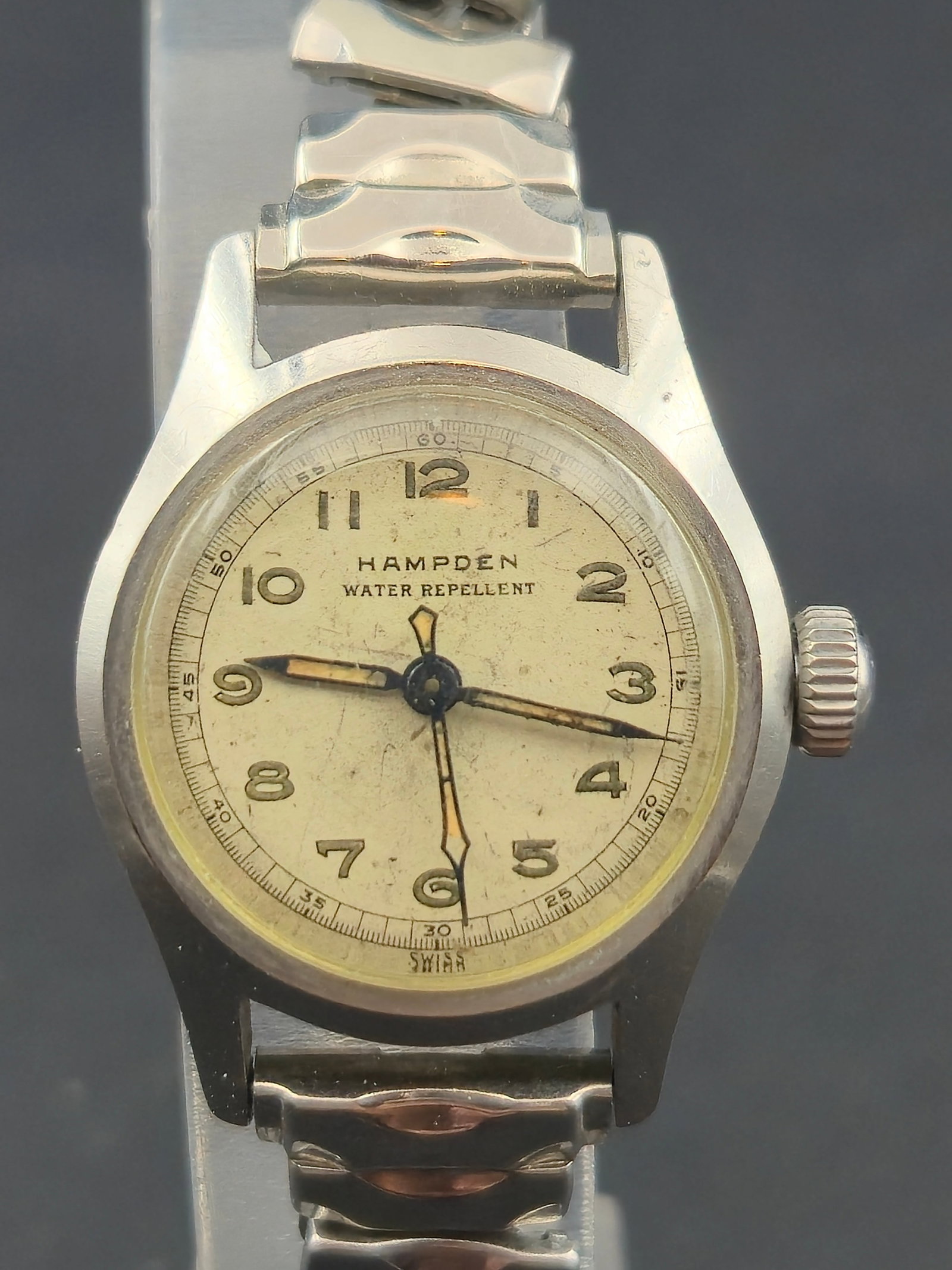 Hampden Swiss Water Repellent Manual Wind Wristwatch c.1940s 24.2mm Runs: Vintage Hampden Watch Company Swiss wristwatch featuring a classic cream dial with applied Arabic numerals and blued steel hands. Dial signed “Hampden – Water Repellent – Swiss.” Stainless