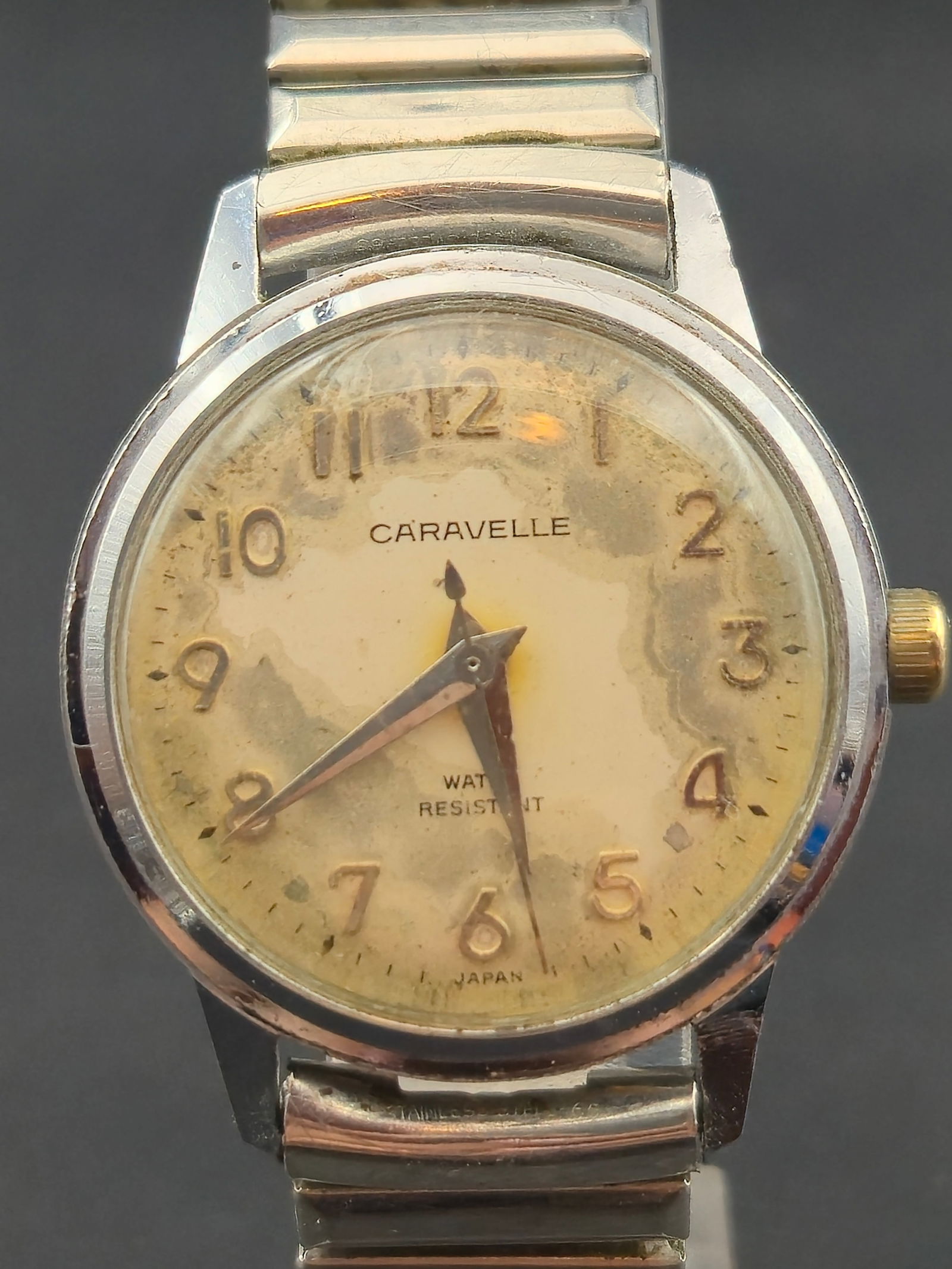 Caravelle by Bulova Vintage Manual Wind Wristwatch c.1960s 31.4mm Patina Dial Runs: Vintage Caravelle by Bulova manual-wind wristwatch with warm aged cream dial showing natural patina, raised Arabic numerals, and classic mid-century handset. Dial signed “Caravelle” and “Wat