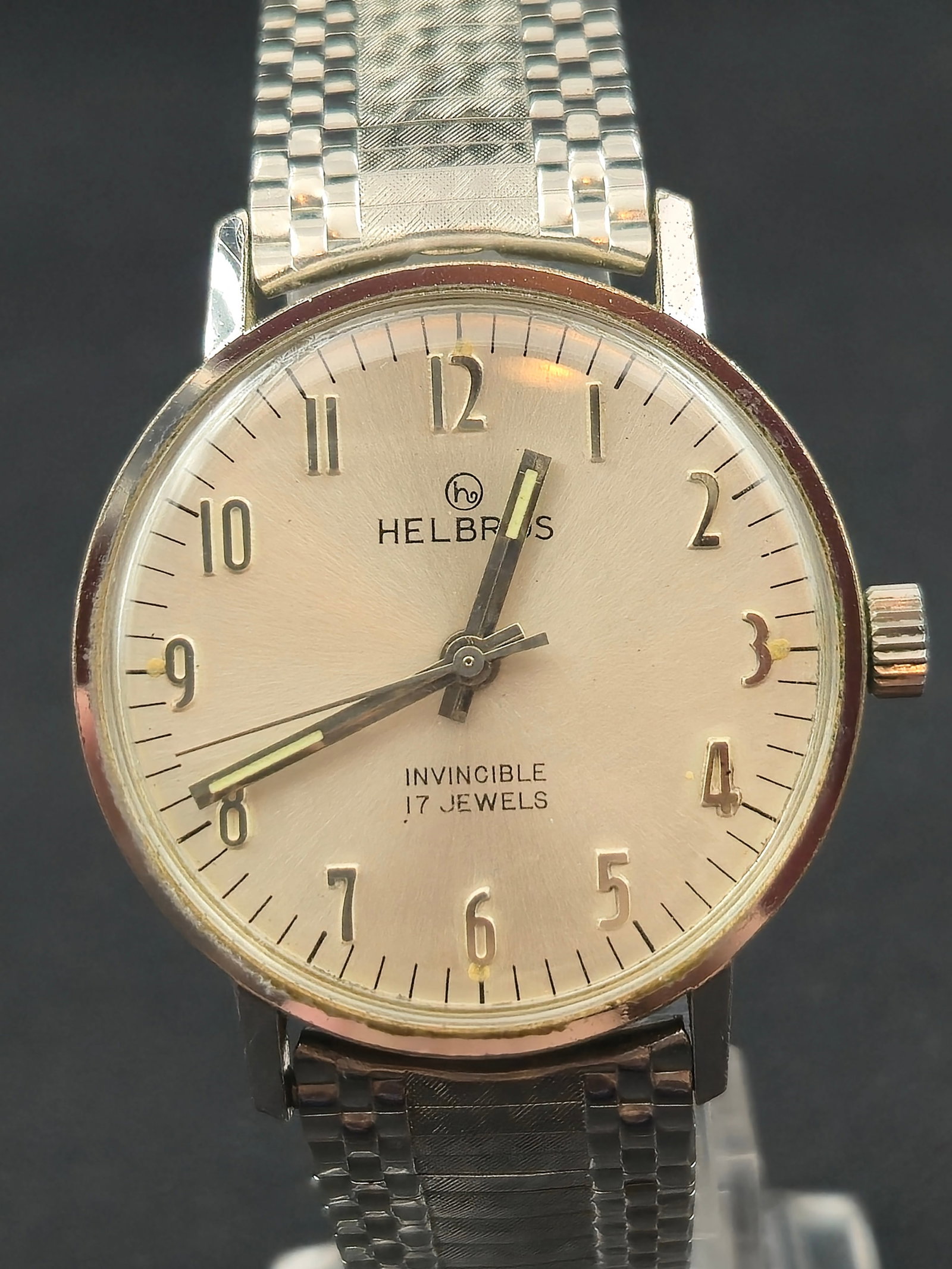 Helbros Invincible 17J Manual Wind Wristwatch c.1960s 34.0mm Silver Dial: Vintage Helbros “Invincible” Swiss manual-wind wristwatch featuring a clean silver sunburst dial with applied Arabic numerals and luminous hands. Dial signed “Helbros Invincible 17 Jewels.&r