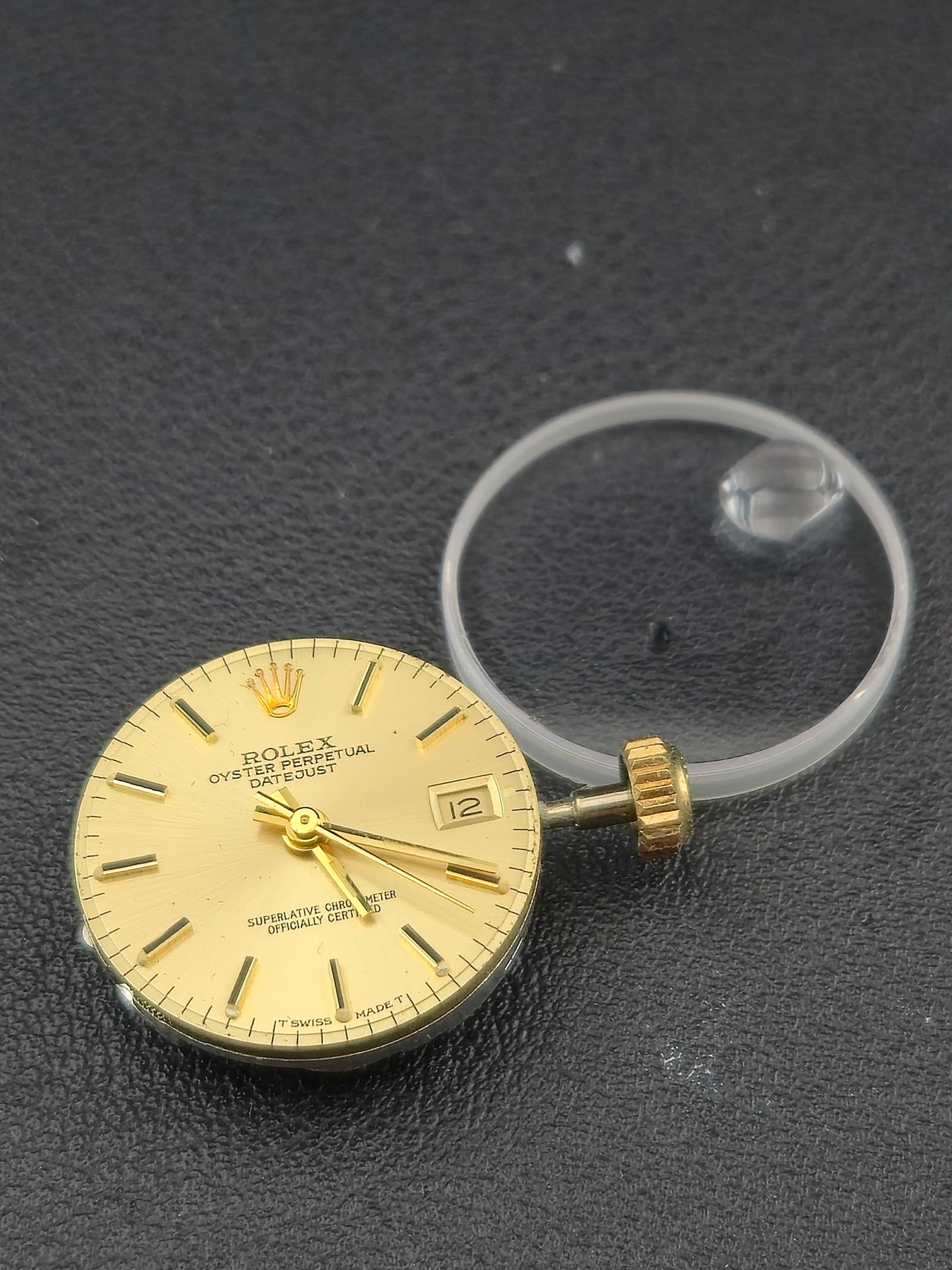 Rolex Caliber 2135 Automatic Movement Gold Datejust Dial Stem Crown Crystal: Original Rolex watch components consisting of a Rolex Caliber 2135 automatic movement, gold Oyster Perpetual Datejust dial, gold hands, signed Rolex crown with attached stem, and acrylic crystal. The