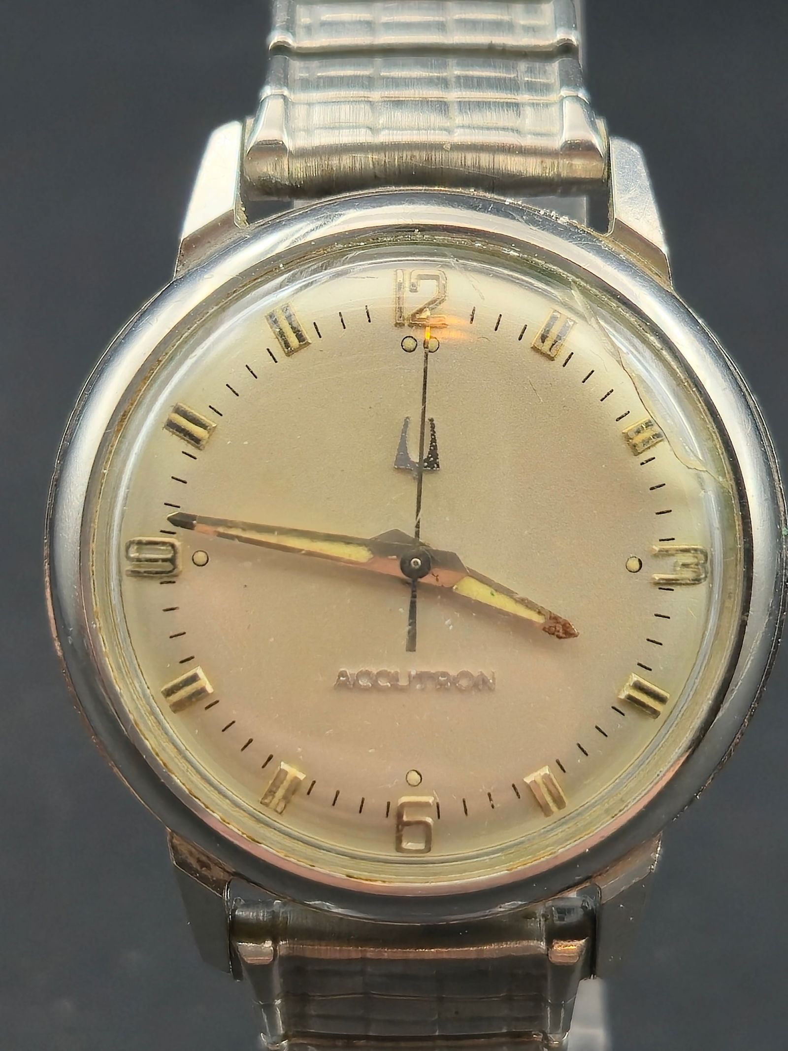 1969 Bulova Accutron 214 Stainless Steel Case Champagne Dial Speidel Band 34.88mm: Bulova Accutron wristwatch with champagne-tone dial. Dial reads ACCUTRON and features applied Arabic numeral hour markers with tuning fork logo above 6 o’clock. Stainless steel case with signed Bulo