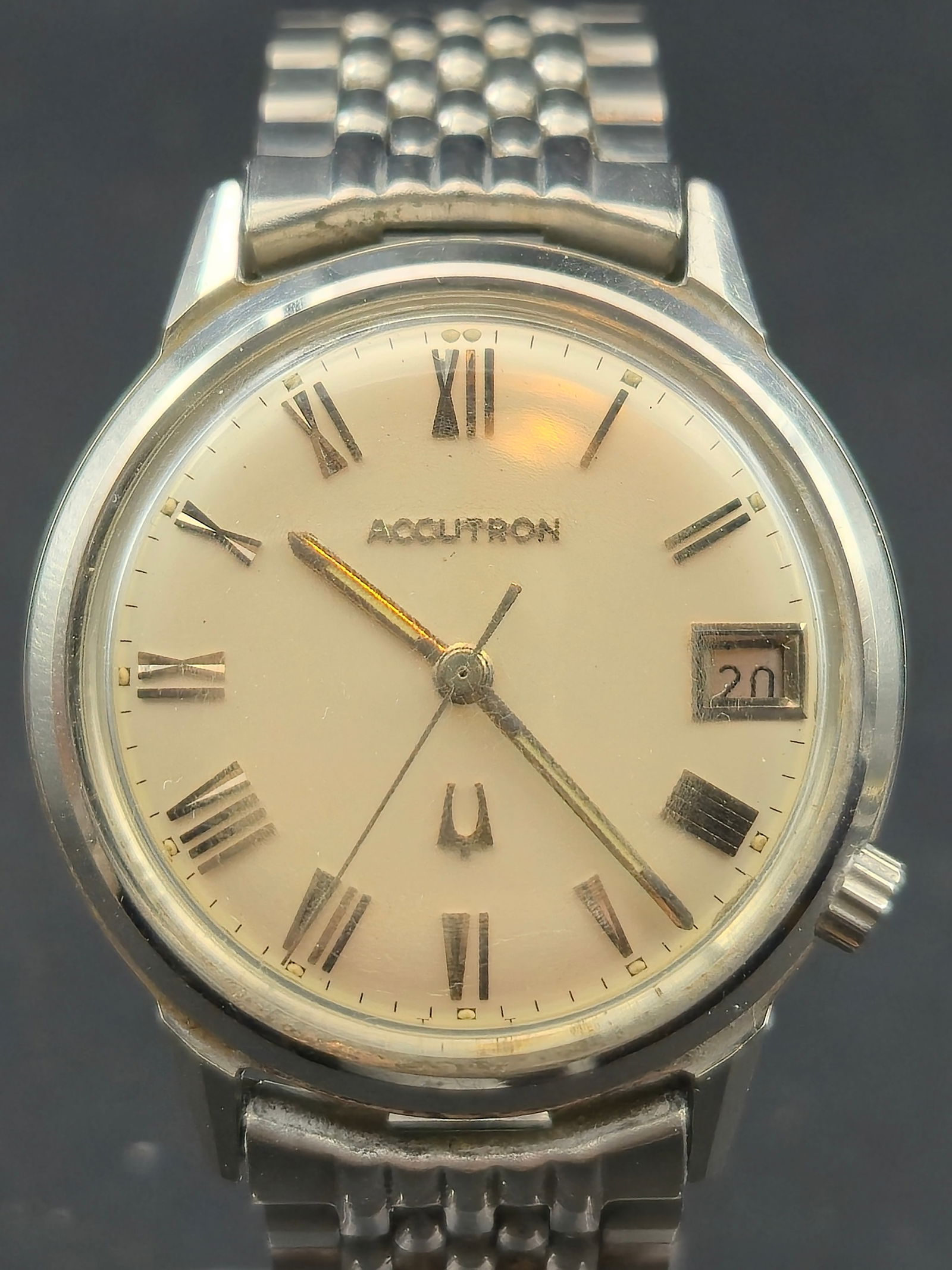 1967 Bulova Accutron 2181 Stainless Steel Roman Dial Speidel BOR 34.60mm: Bulova Accutron wristwatch featuring a silver sunburst dial with applied Roman numeral hour markers, tuning fork logo above 6 o’clock, and framed date window at 3 o’clock displaying 20. Dial is si