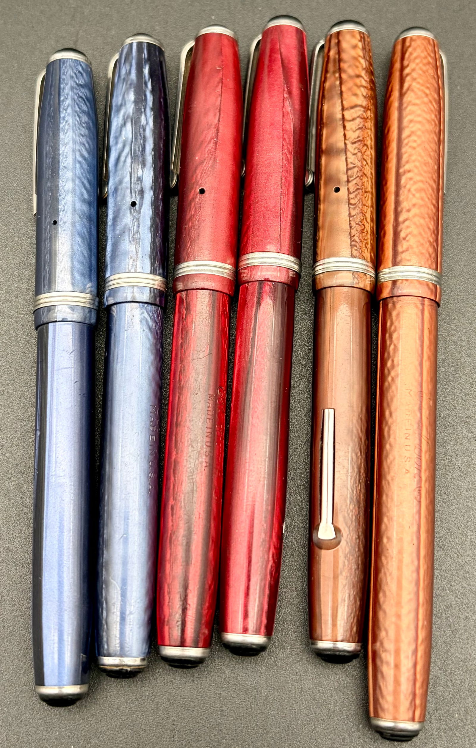 Vintage Fountain Pen Collection – 6 Celluloid Pens in Blue, Red & Copper – Esterbrook Nibs: A visually stunning group of six vintage fountain pens in classic mid-century colors: pearlescent blues, rich ruby reds, and warm copper/amber marbled celluloid. These pens date from the 1930s–1950s