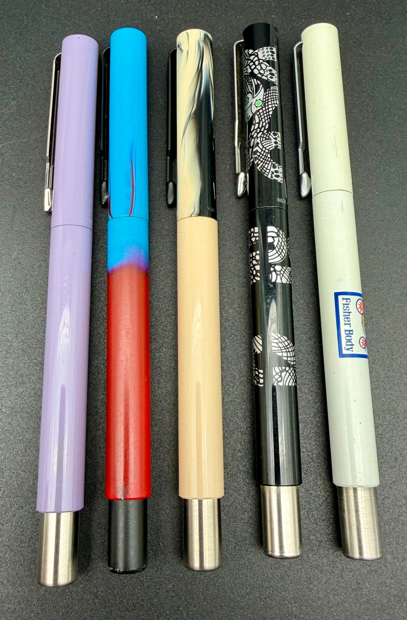 Vintage Fisher Body Rollerball Pens – Color Lot: Striking lot of five vintage rollerball-style pens featuring bold colors and distinctive finishes. This group includes pastel lavender, bright turquoise with red fade, marbled cream, graphic black-and