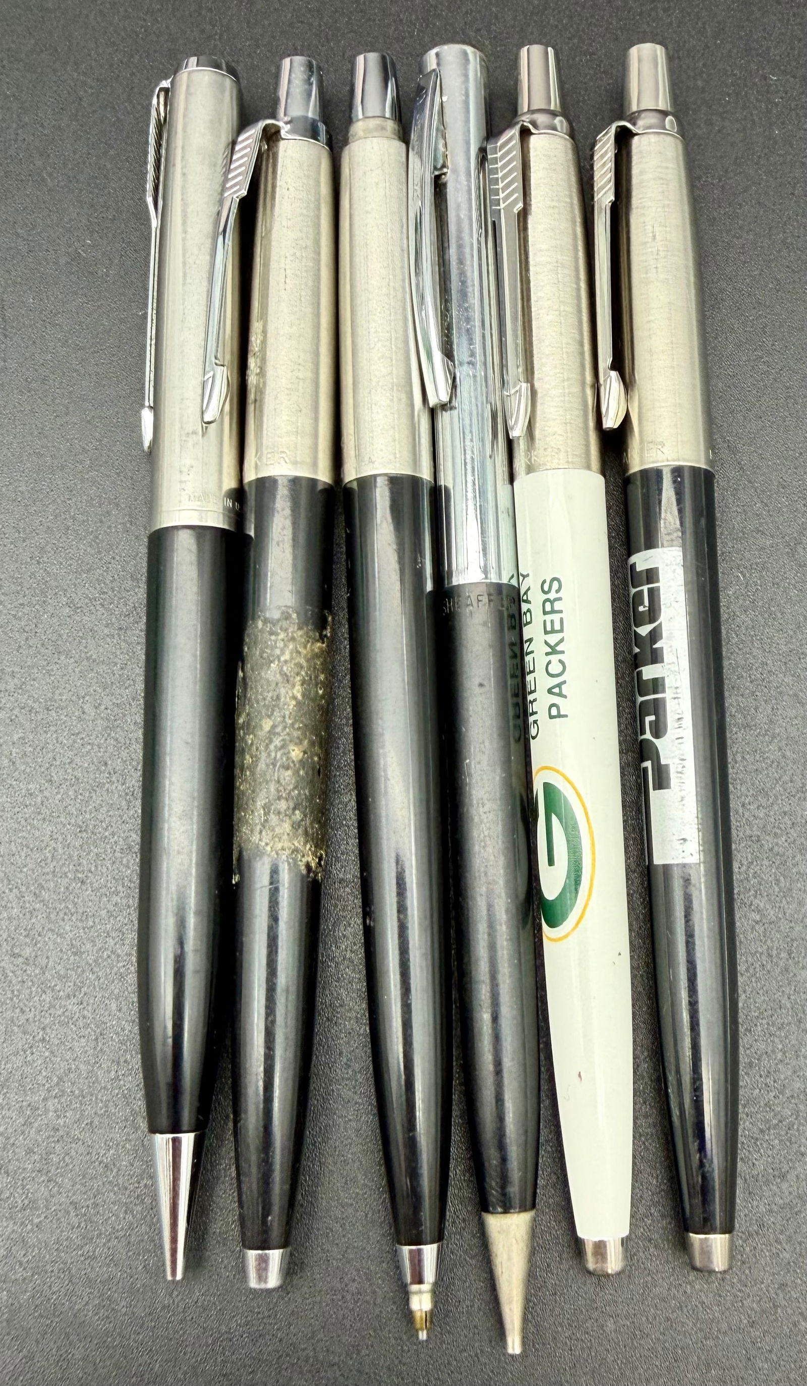 6 Vintage Parker-Style Pens – Advertising Lot: Attractive lot of six vintage ballpoint pens in classic mid-century styling. Most feature brushed metal upper barrels with black lower sections, echoing the iconic Parker look. Two are advertising pen