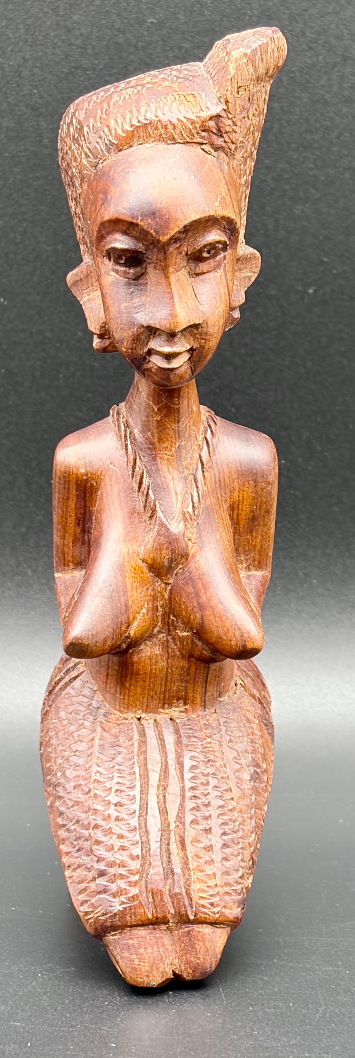 Hand-Carved Wooden Figure – Folk Art Sculpture: Striking hand-carved wooden figure depicting a woman in a traditional pose with palms together. The sculpture features expressive facial carving, elongated proportions, and finely textured details in
