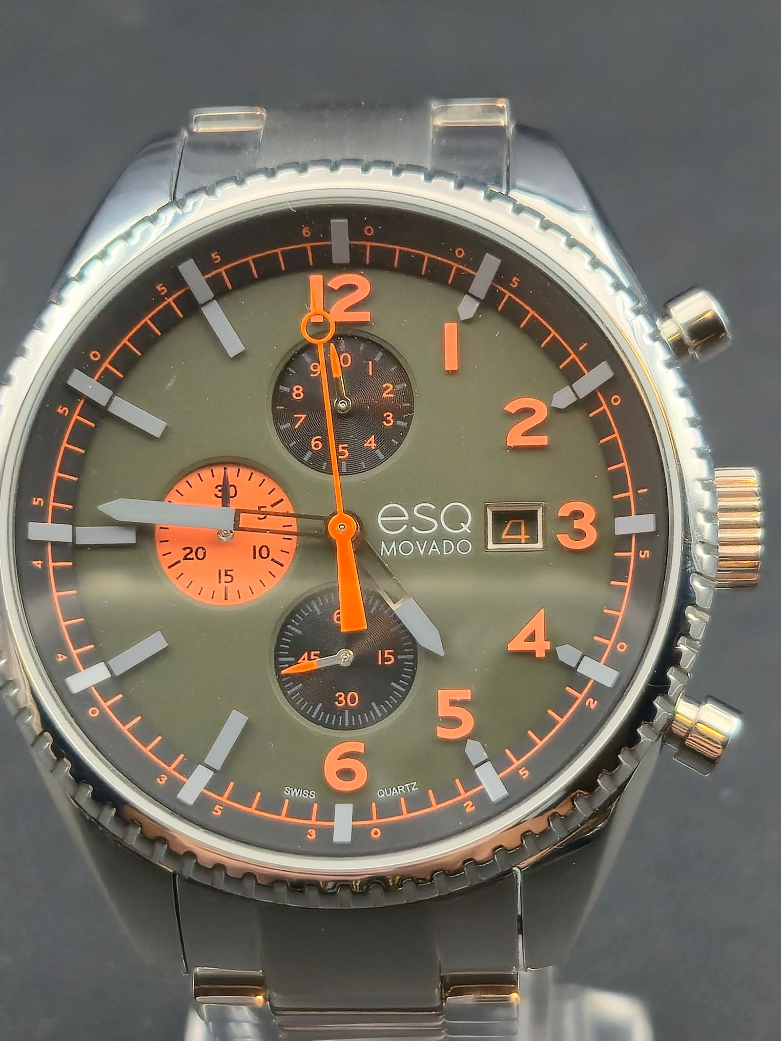 ESQ by Movado Swiss Quartz Chronograph Date Ref 48.1.14.5682 Forest Green Dial 44mm: ESQ by Movado Swiss quartz chronograph wristwatch featuring a stainless steel case and bracelet with a forest green dial and orange accents. The dial is marked “ESQ MOVADO” and “SWISS QUARTZ