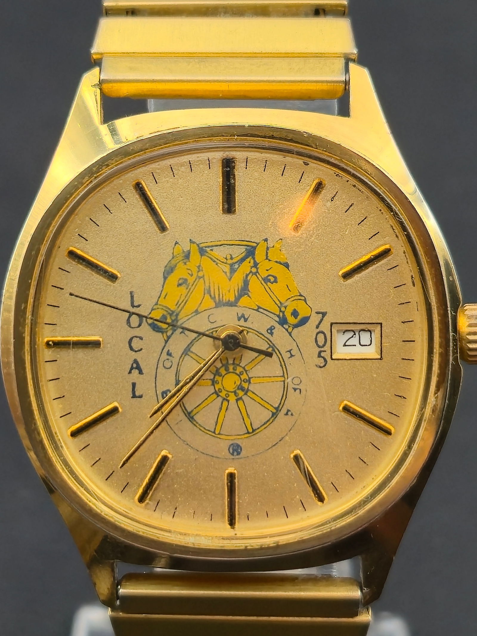 1990s “Local” Horse & Wagon Calendar Watch – Gold-Tone Case – Quartz – 33mm –: Vintage “Local” quartz wristwatch featuring a gold-tone dial with horse & wagon motif, applied baton hour markers, and date calendar at 3 o’clock. Gold-tone case paired with a matching gold-