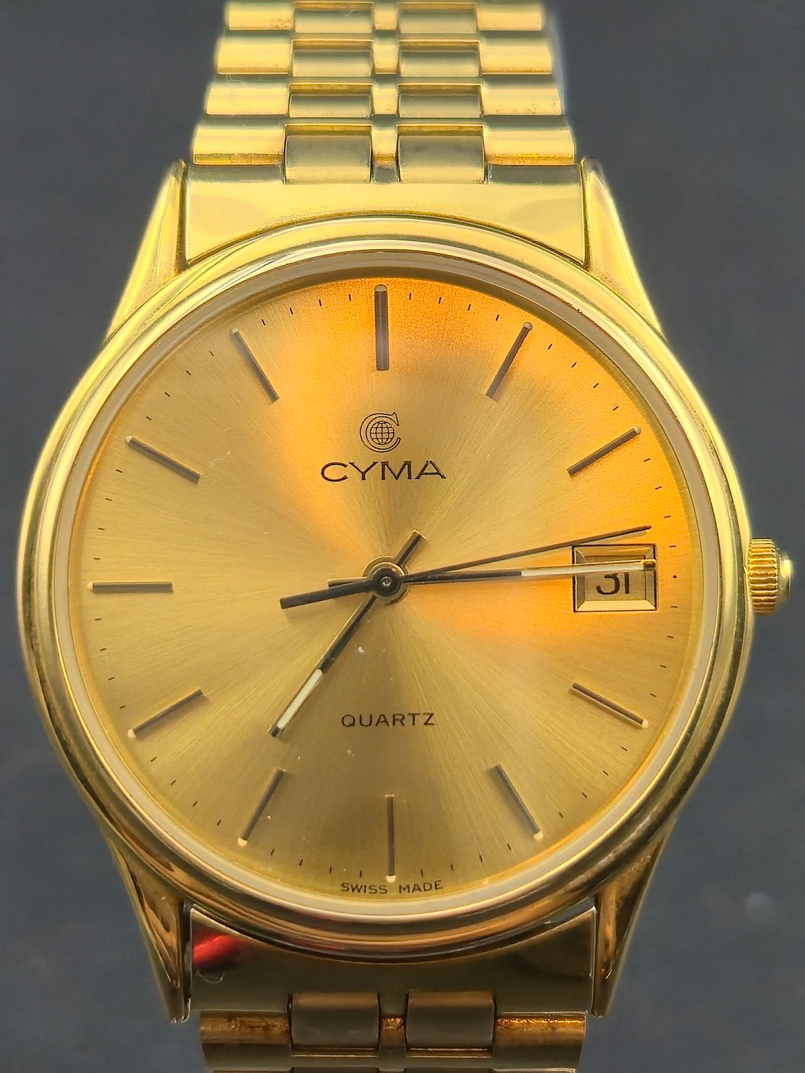 1990s Cyma Quartz Date Ref. 630-103 YP – Plaqué Or L10M – 33mm – Running: Swiss-made Cyma Quartz wristwatch, reference 630-103 YP, featuring a Plaqué Or L10M (10-micron gold-plated) case and matching bracelet. Champagne sunburst dial with applied baton hour markers and dat