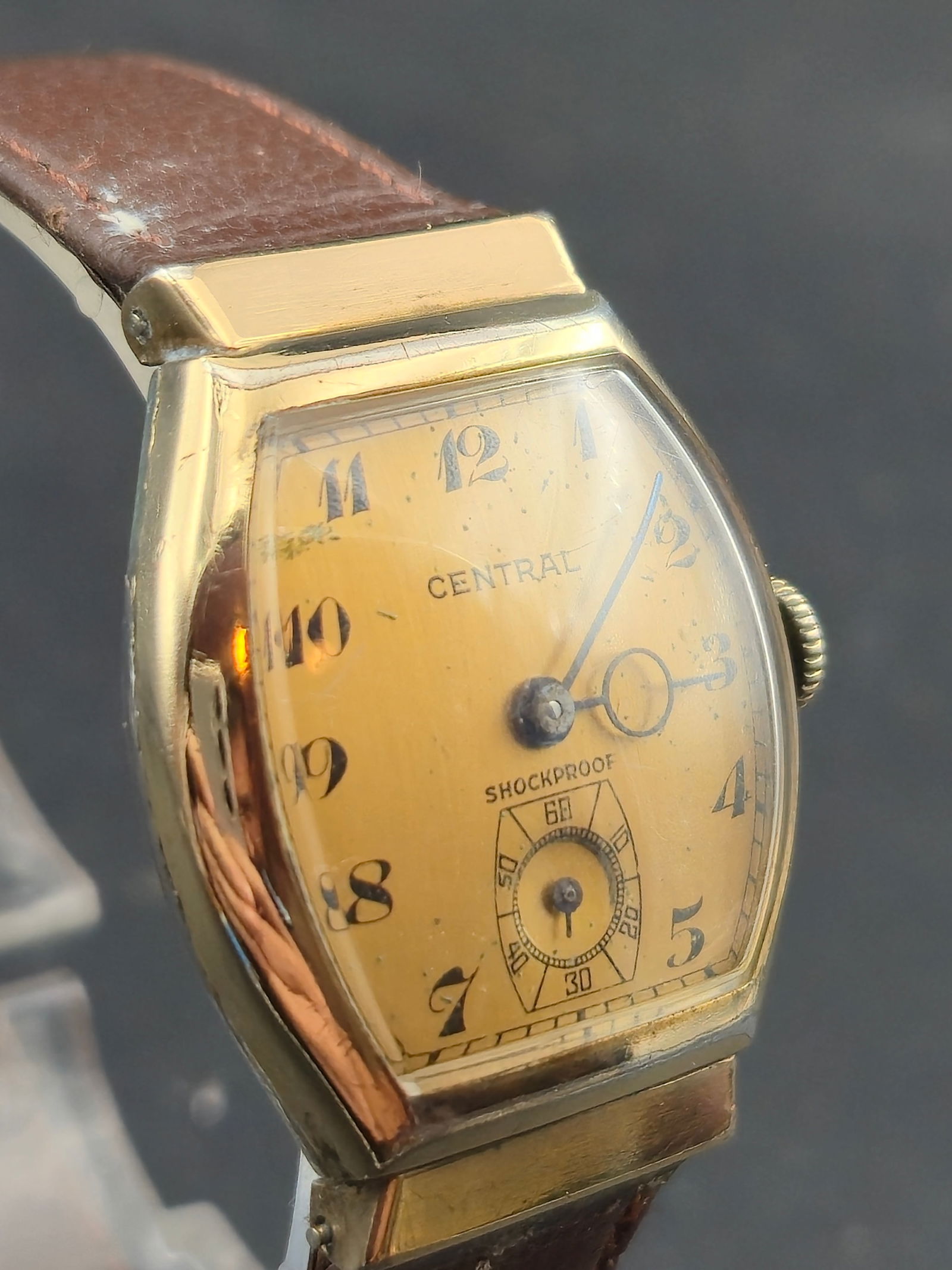 1930s Central Shockproof 21J Tonneau Wristwatch Gold-Tone: Vintage Central Watch Co. tonneau-case wristwatch featuring an early shockproof design with small-seconds subdial. Dial is signed CENTRAL with Arabic numerals and original blued steel hands. The watch