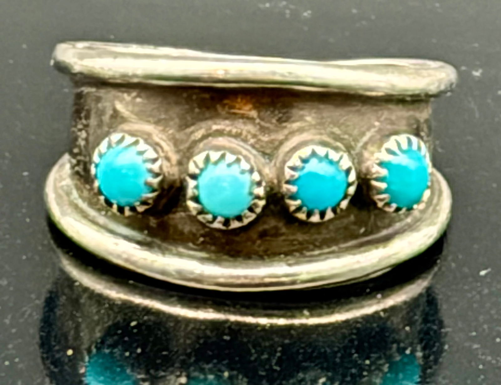 Vintage Southwestern Sterling Silver Band Ring with Four Turquoise Stones: Charming vintage Southwestern-style band ring crafted in sterling silver and set with four petite turquoise cabochons. Each stone is framed in a delicate sawtooth bezel and evenly spaced across the fr