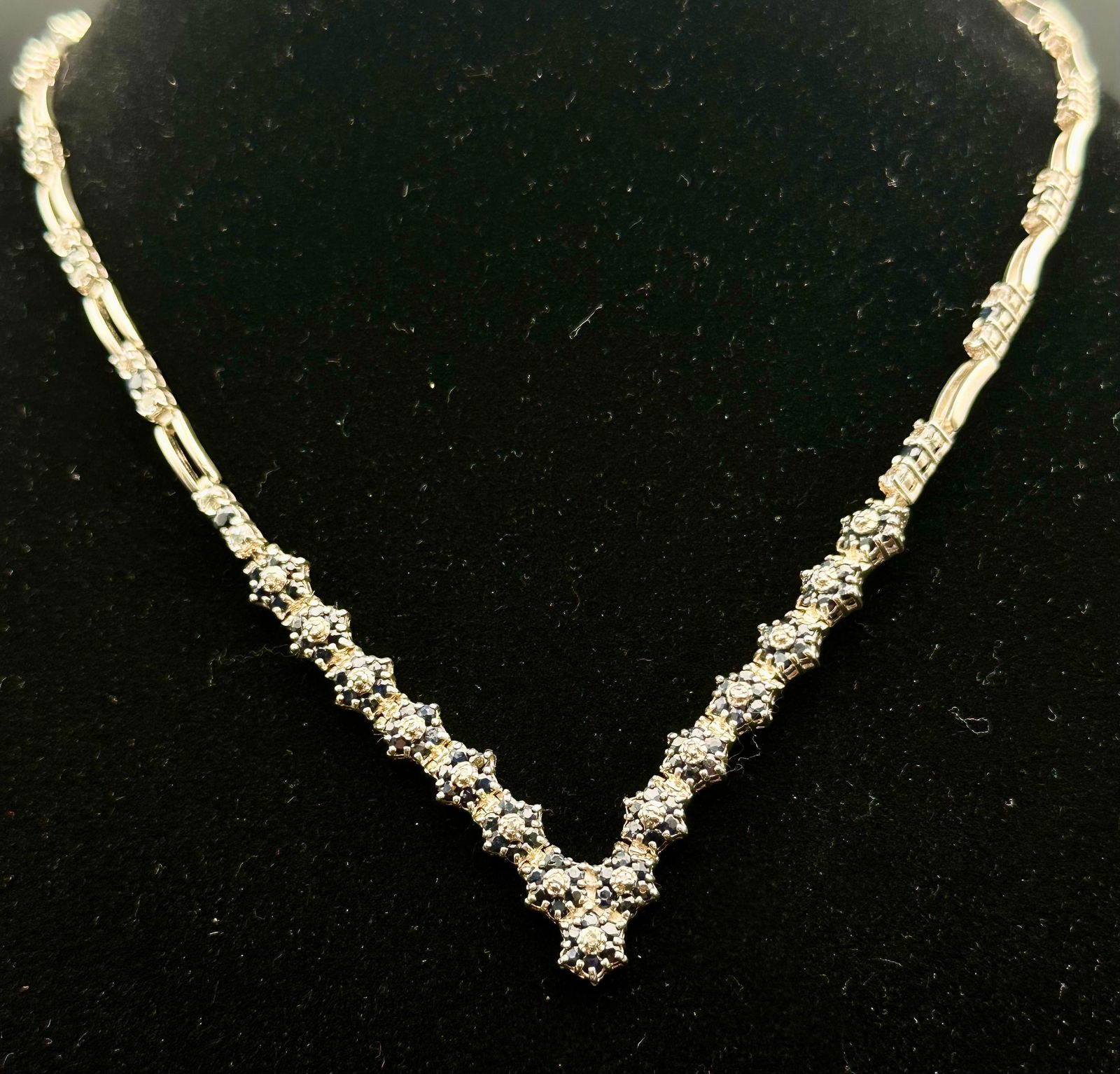 Sterling Silver Blue Sapphire & Clear Stone Cluster Necklace 33g: Sterling silver necklace marked 925 featuring dark blue sapphire-style stones accented with clear diamond-style clusters throughout. Elegant articulated design with repeating floral cluster pattern.To