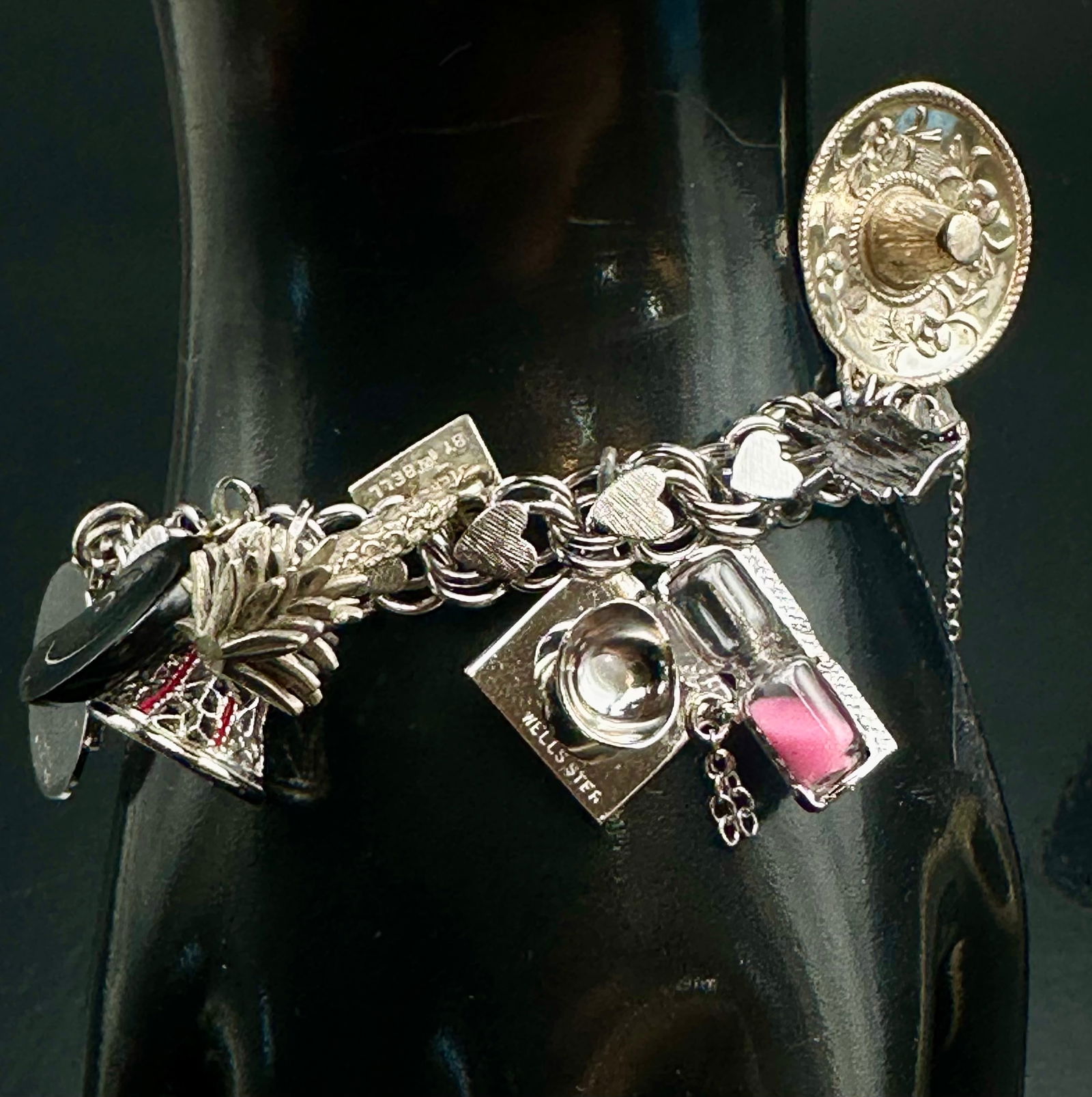 Vintage Elco Sterling Silver Charm Bracelet 55g: Vintage Elco sterling silver charm bracelet featuring a heart link chain with multiple travel, novelty, and souvenir charms including sombrero, hourglass, camera, enamel religious medal, and additiona
